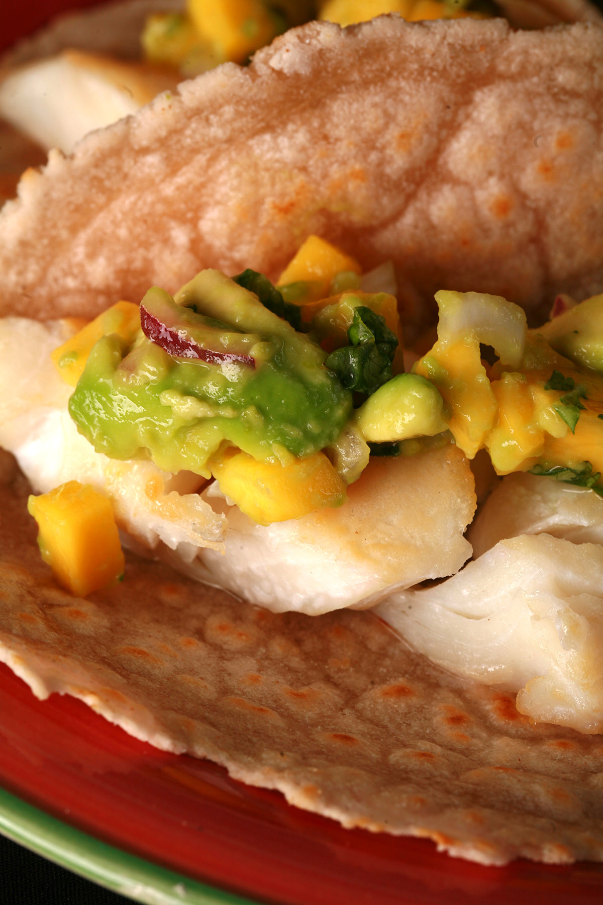 Cassava flour paleo fish tacos, with mango salsa, on a red plate.