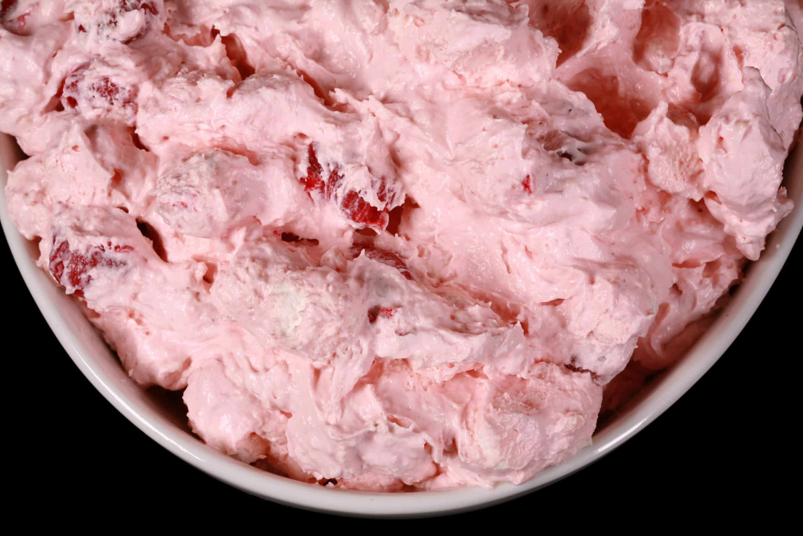 A serving bowl of bright pink cherry cheesecake fluff salad.