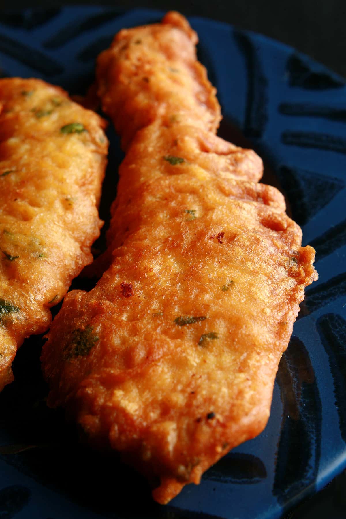 Several chicken pakora strips on a blue plate.
