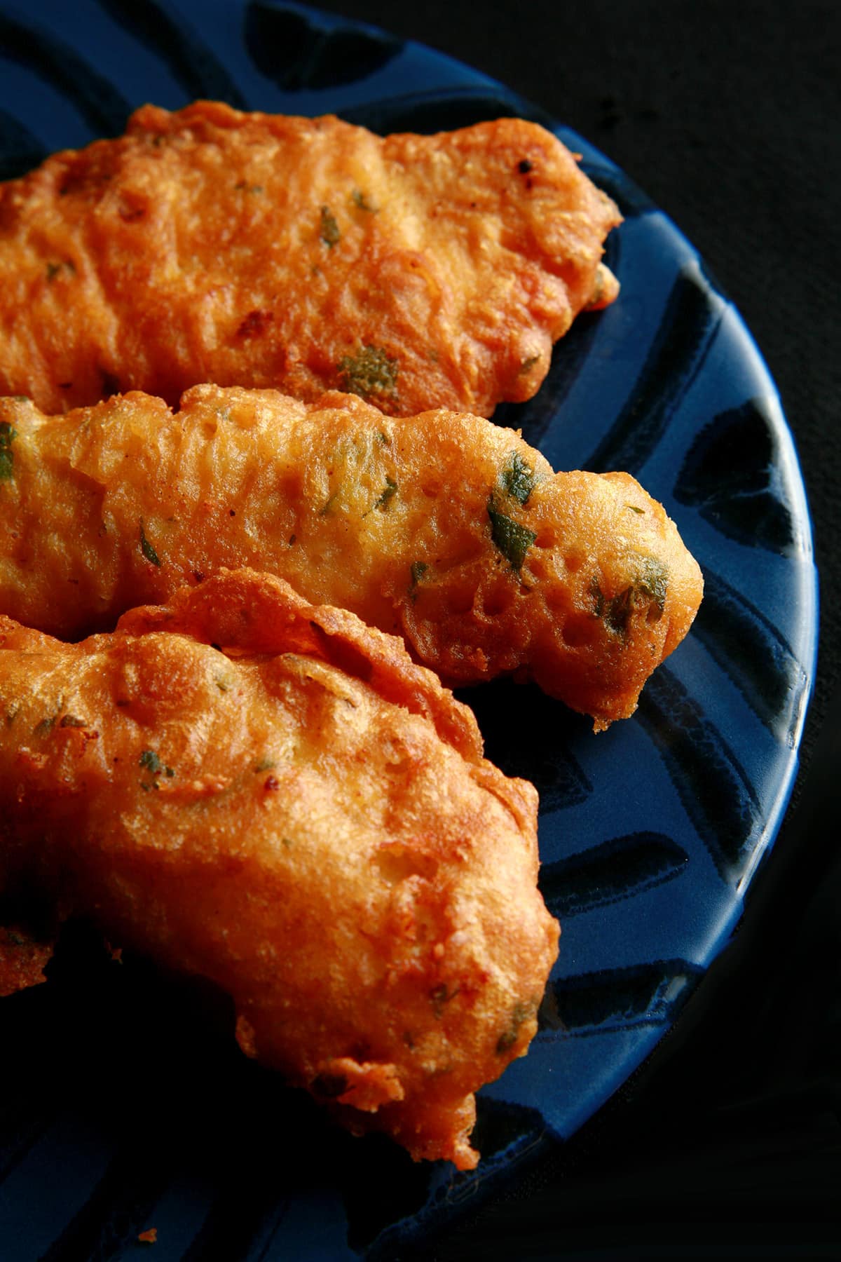 Several chicken pakora strips on a blue plate.