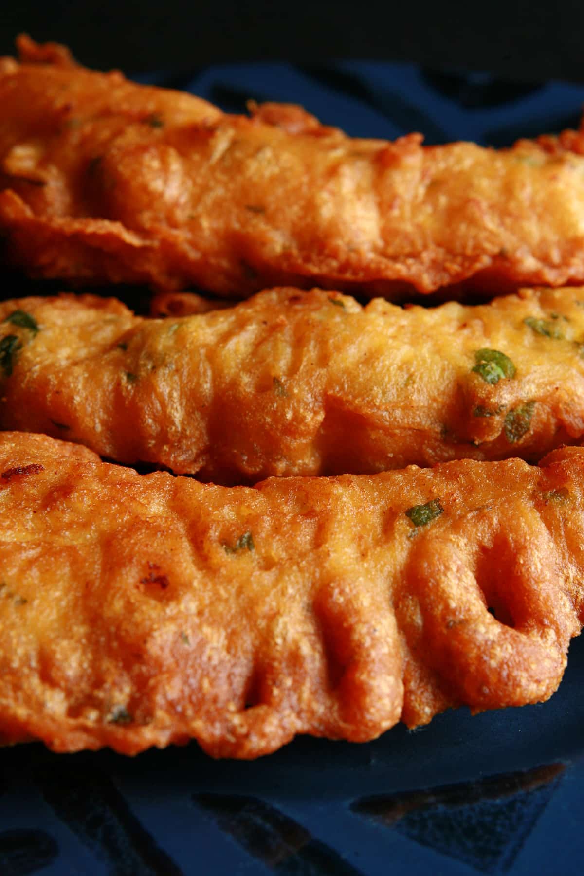 Several chicken pakora strips on a blue plate.
