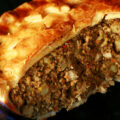 A close up photo of a cut-open chicken mushroom tourtiere pie. The crust has maple leaves on it.