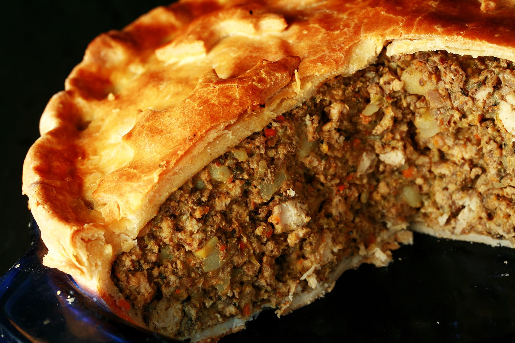 A close up photo of a cut-open chicken mushroom tourtiere pie. The crust has maple leaves on it.