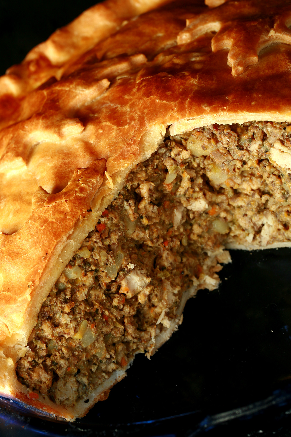 A close up photo of a cut-open chicken mushroom tourtiere pie. The crust has maple leaves on it.