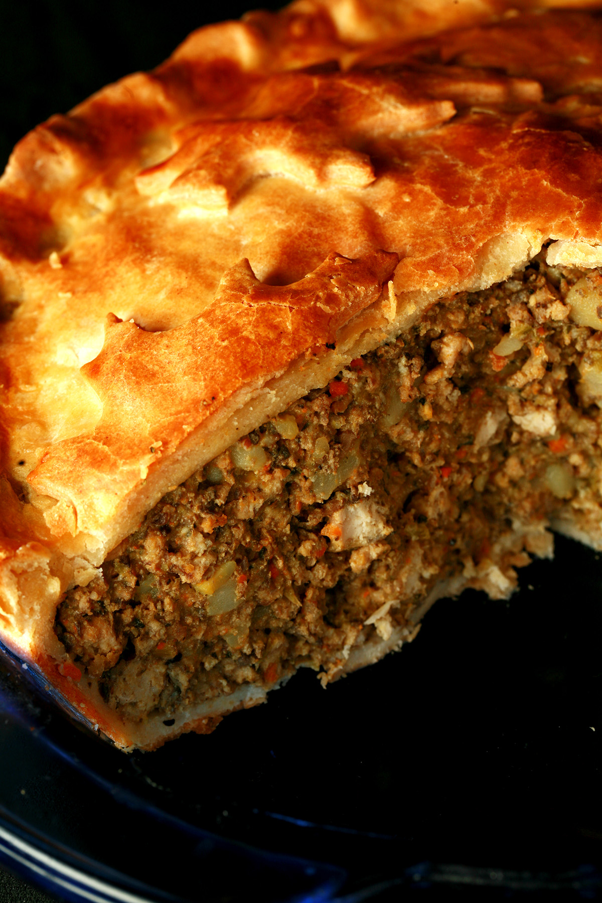 A close up photo of a cut-open meat pie. The crust has maple leaves on it.