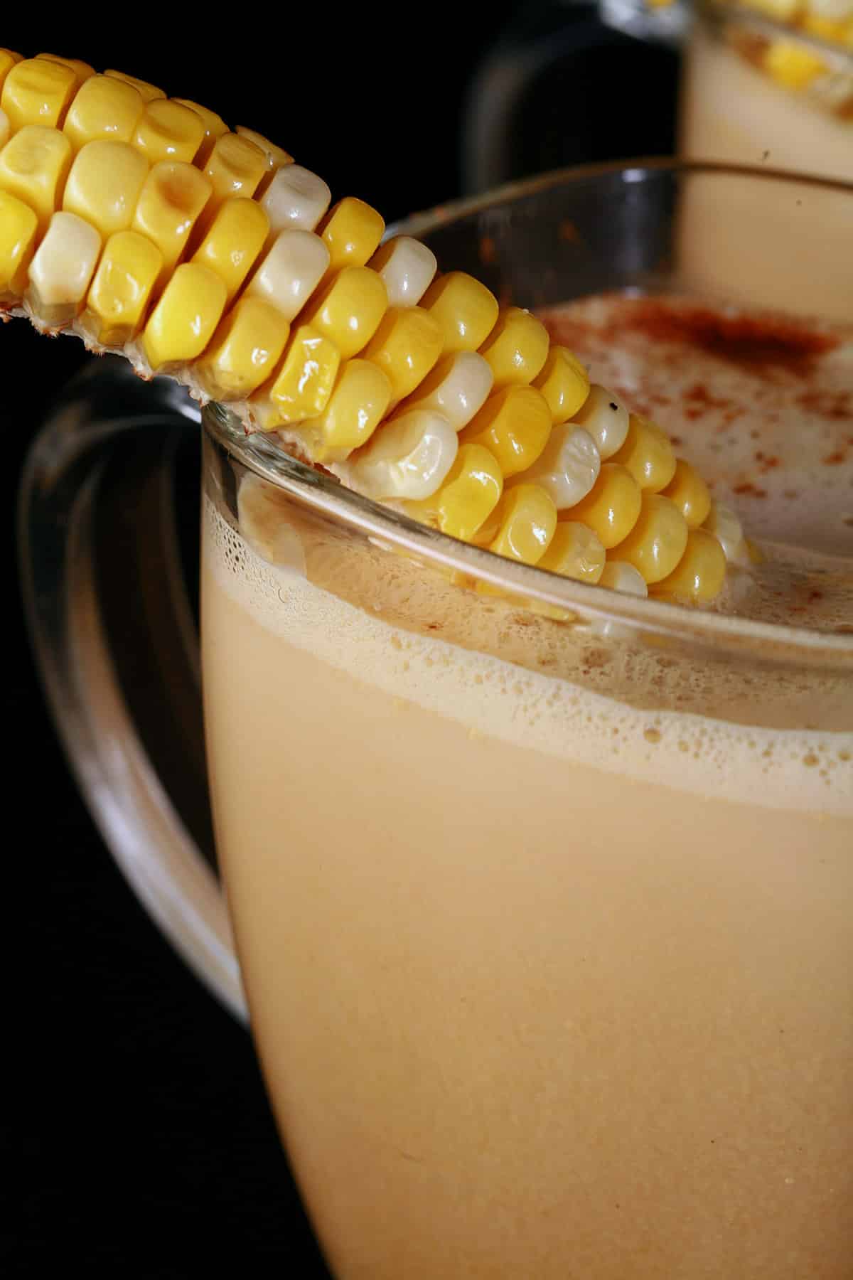 A close up photo of a glass mug of corn cappuccino.