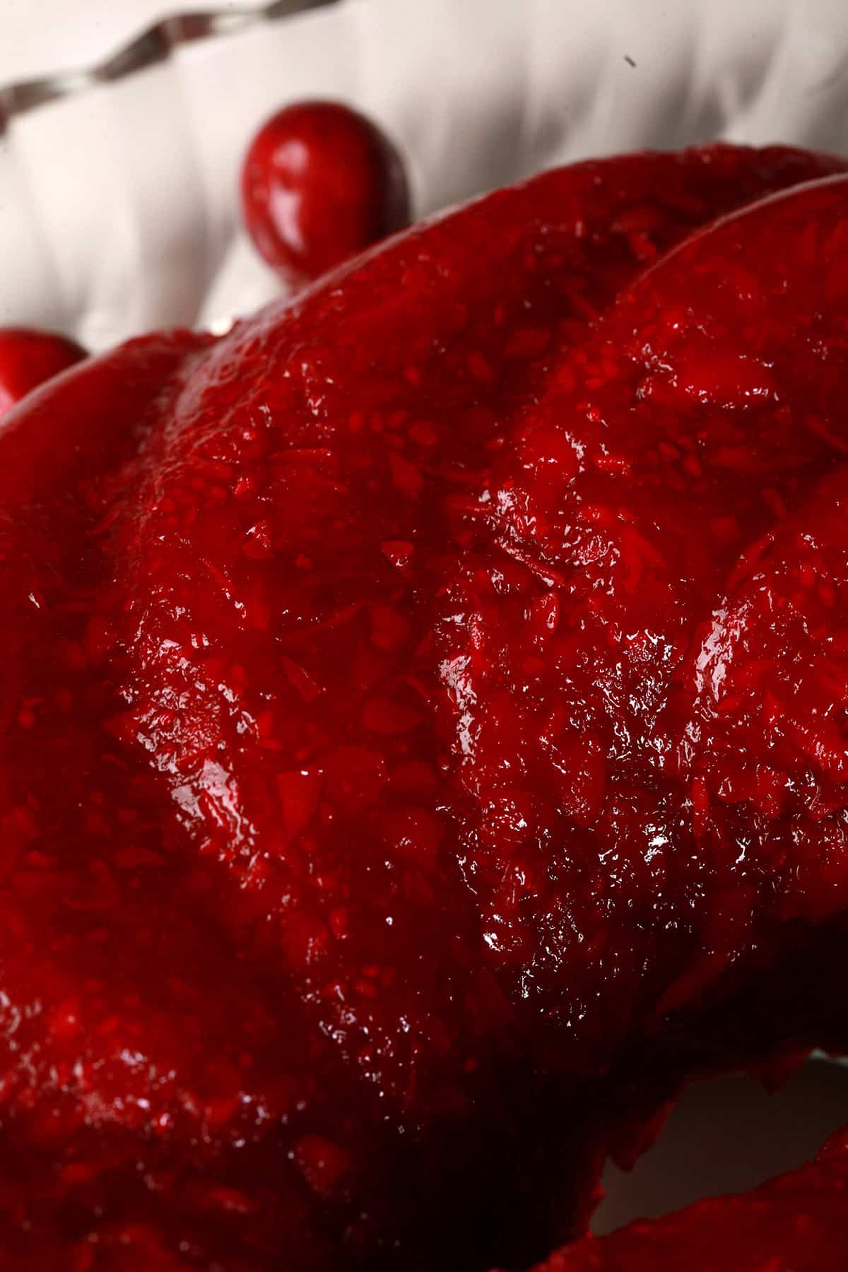 A molded cranberry Jello salad on a glass plate.