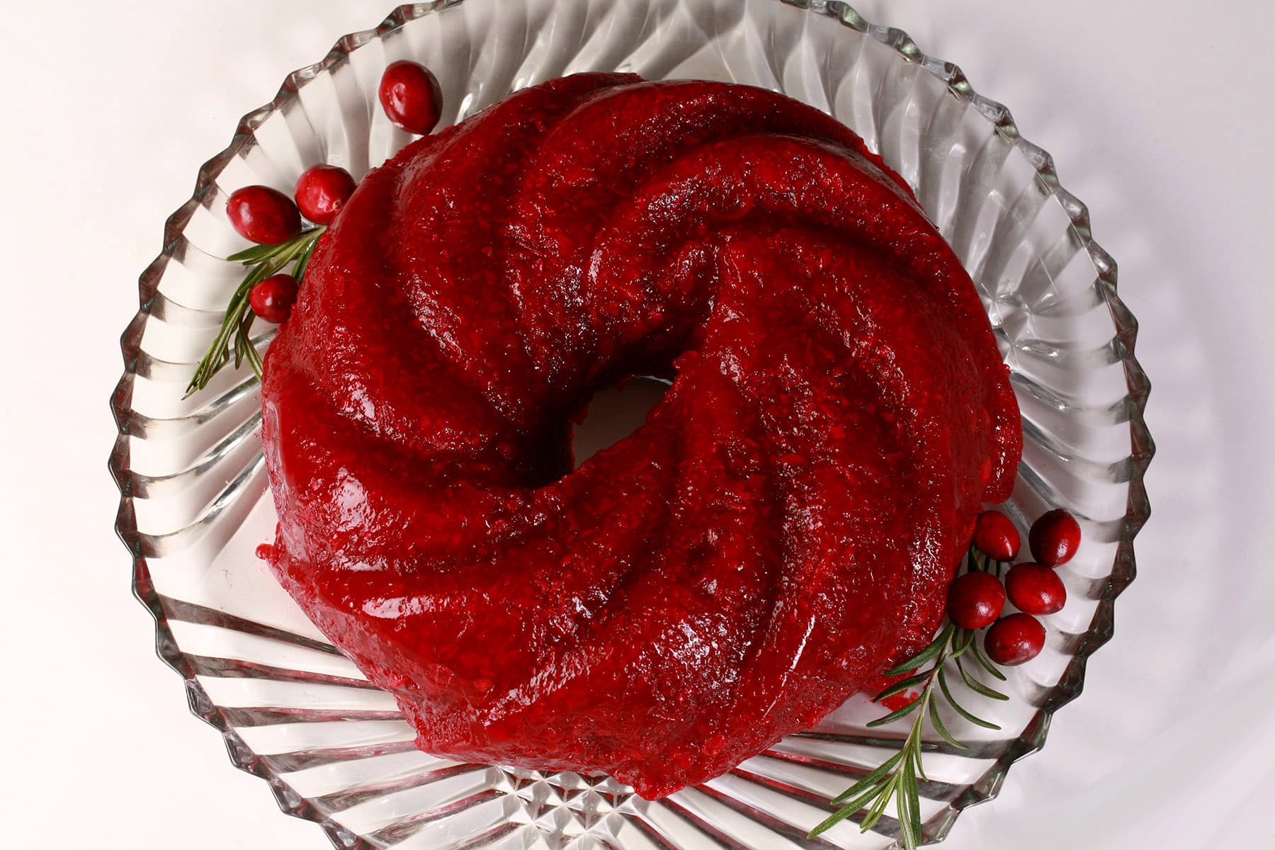 A molded cranberry Jello salad on a glass plate.