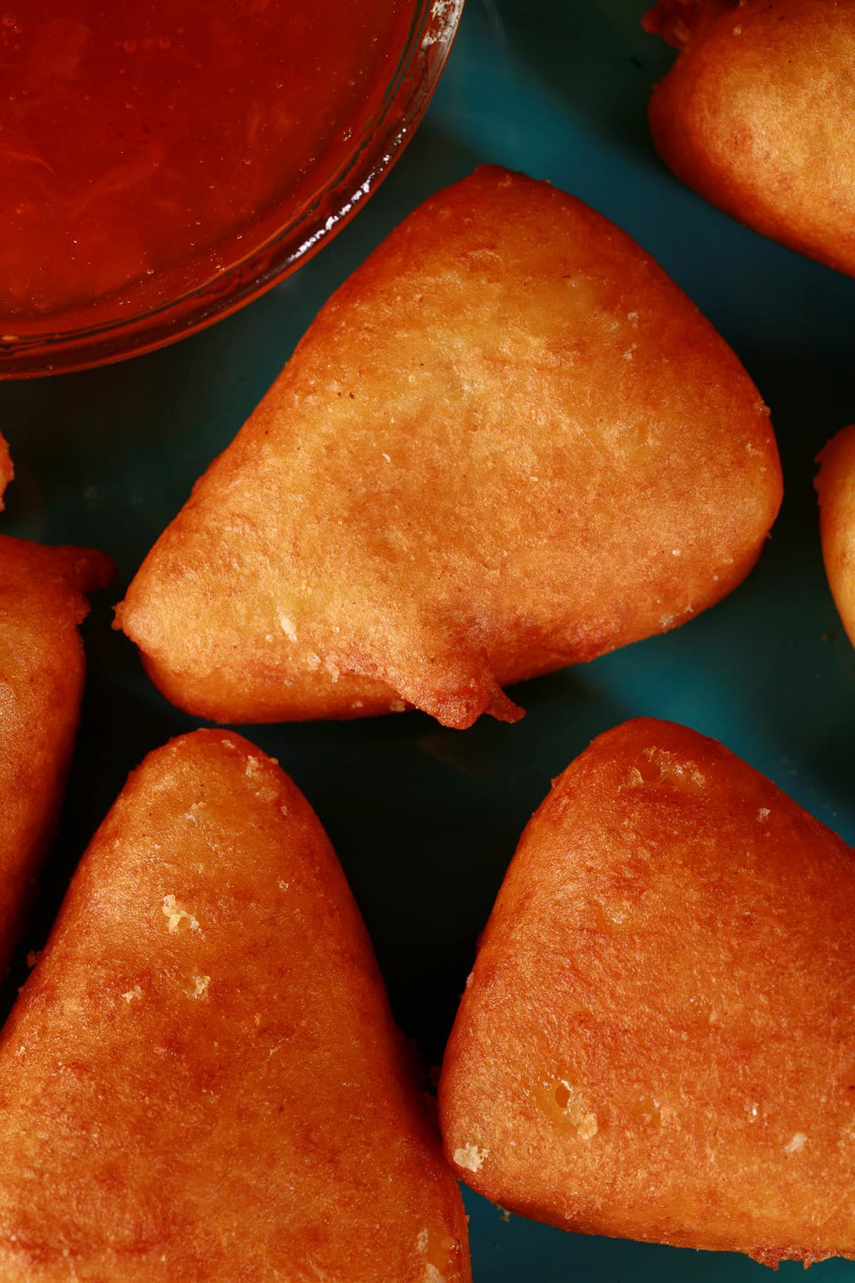 A plate of battered, deep fried brie cheese wedges, around a bowl of apricot preserves.