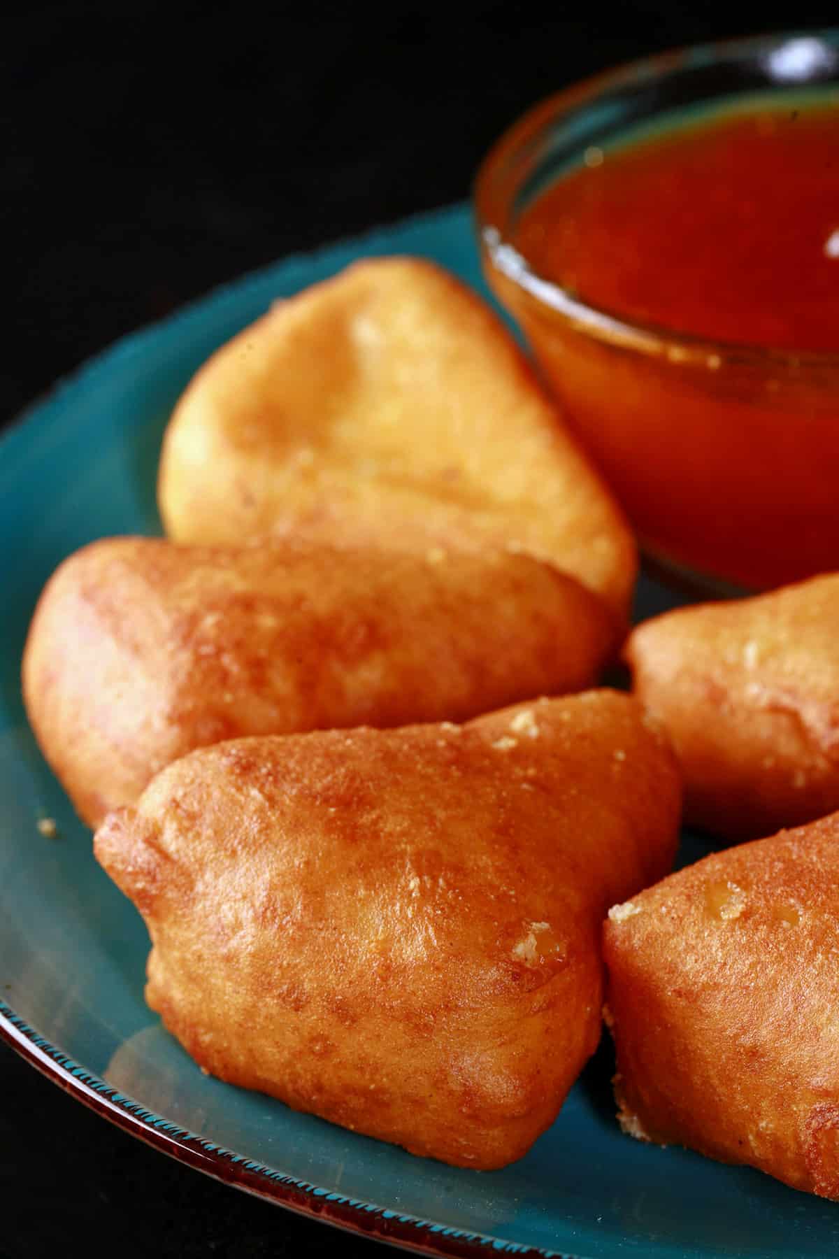 A plate of battered, deep fried brie cheese wedges, around a bowl of apricot preserves.