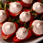 A white plate with deviled strawberries, filled with a cream cheese and balsamic vinegar whipped cream.
