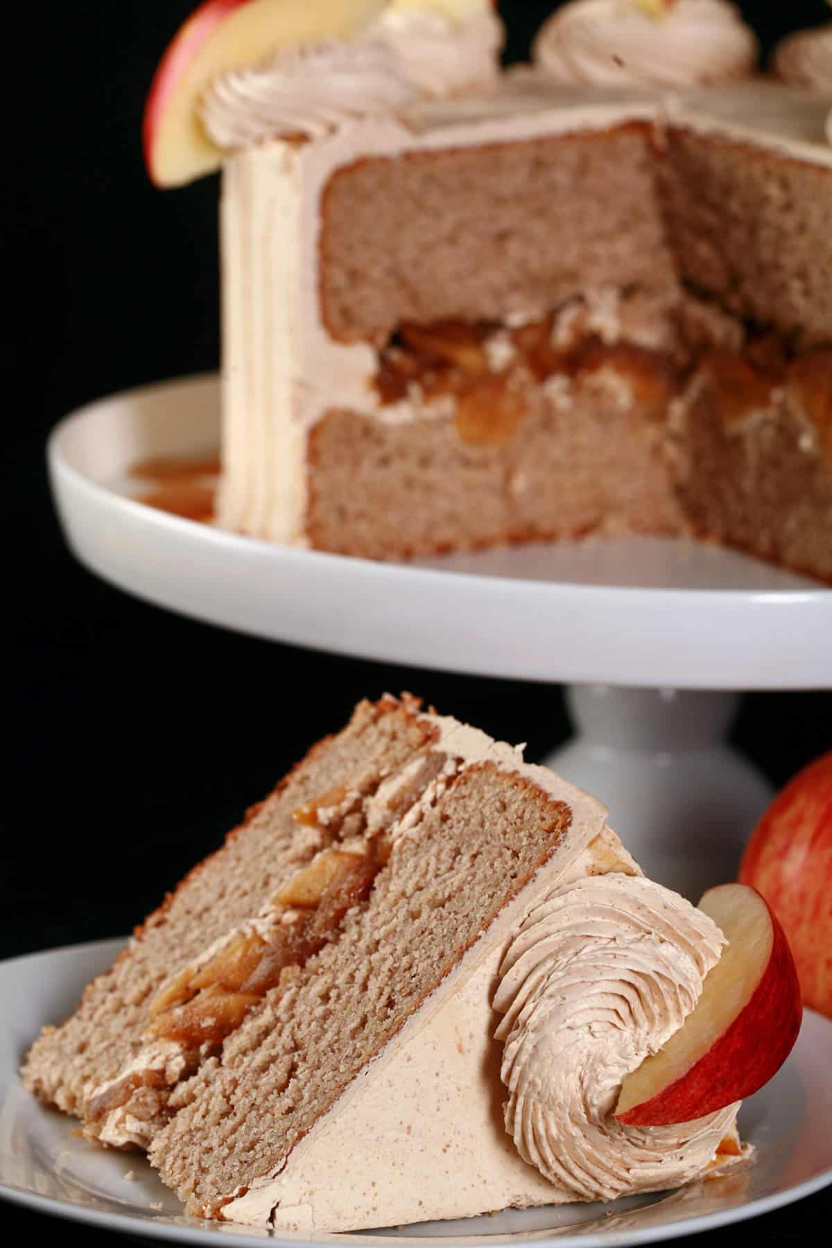A slice of gluten-free apple cake on a plate in front of the whole gluten free apple cake.