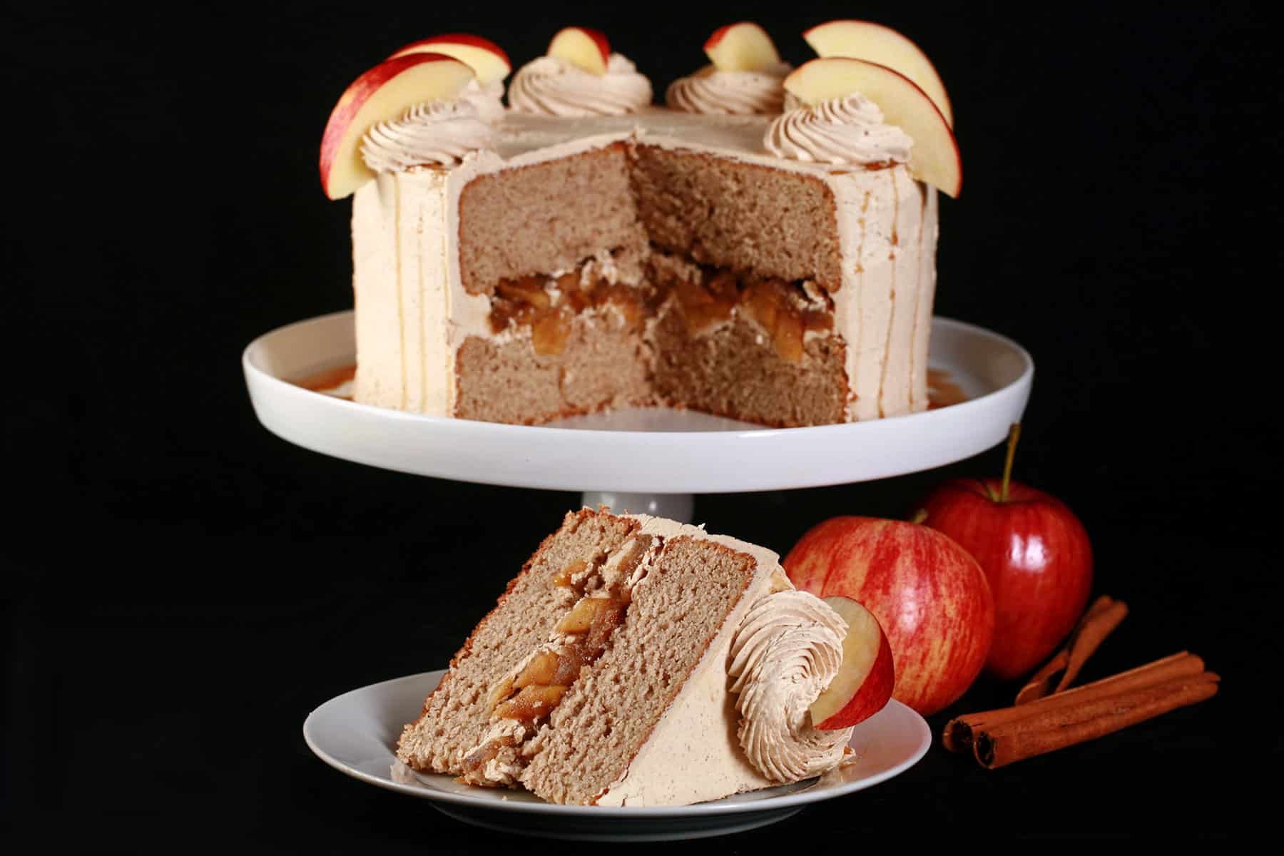 A slice of gluten-free apple cake on a plate in front of the whole gluten free apple cake.