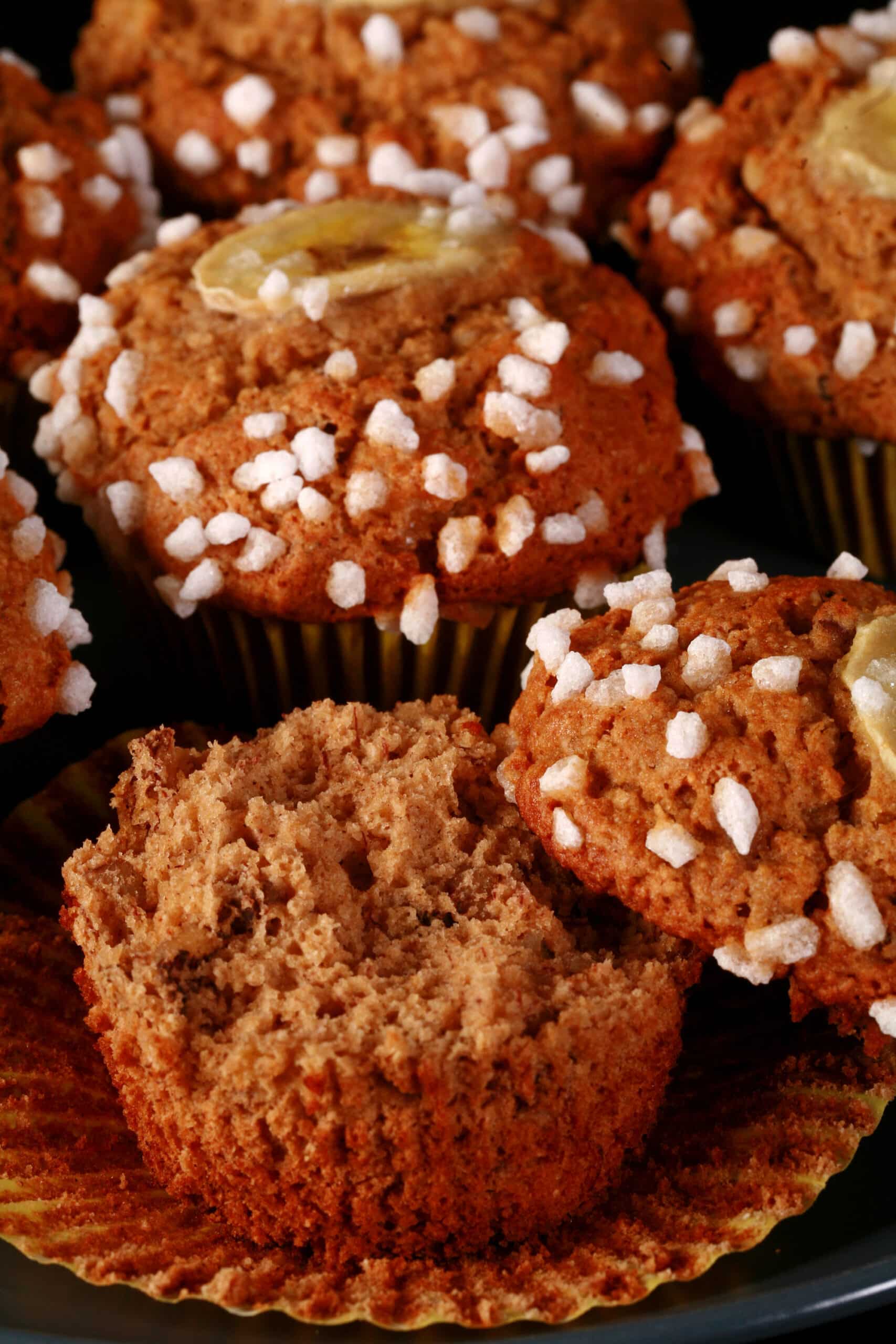 A plate of gluten-free banana muffins, topped with coarse sugar and banana slices.