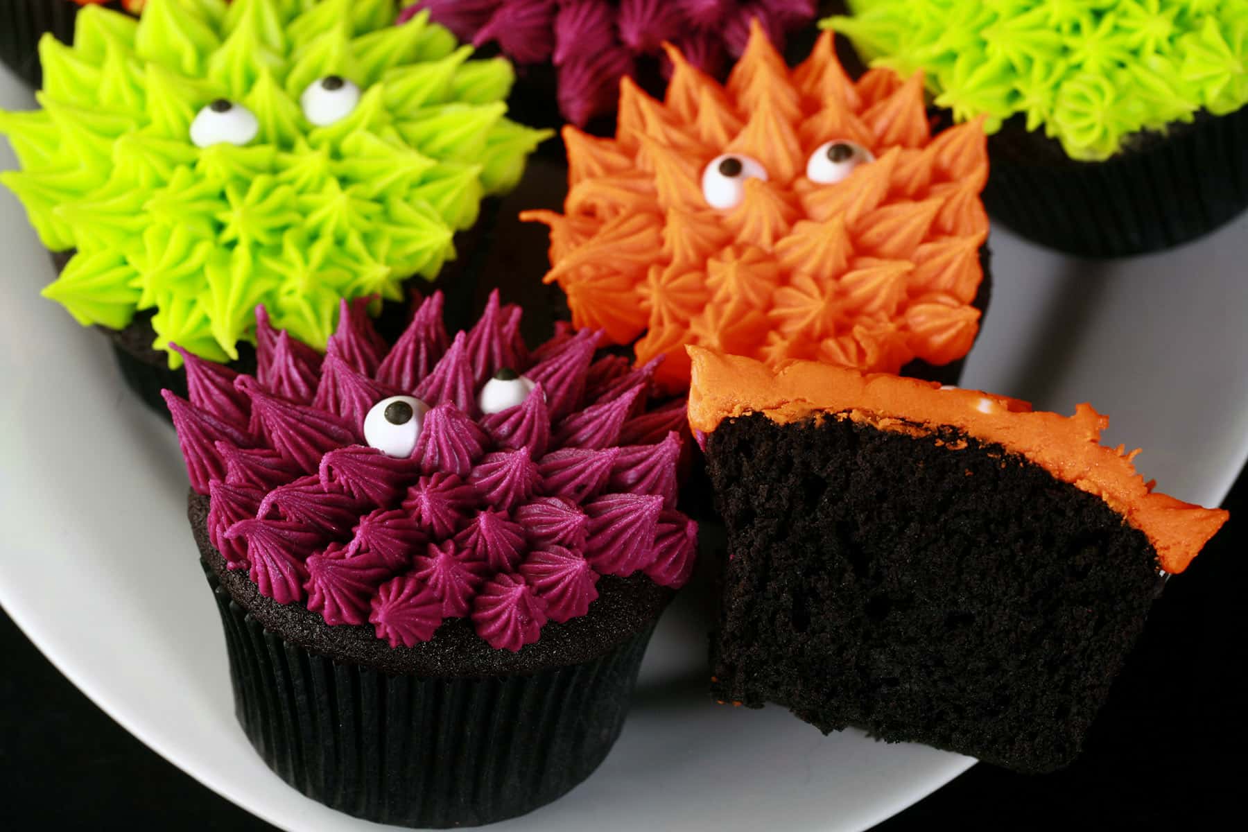 Several brightly coloured gluten free halloween cupcakes, made with gluten-free black velvet cupcakes.