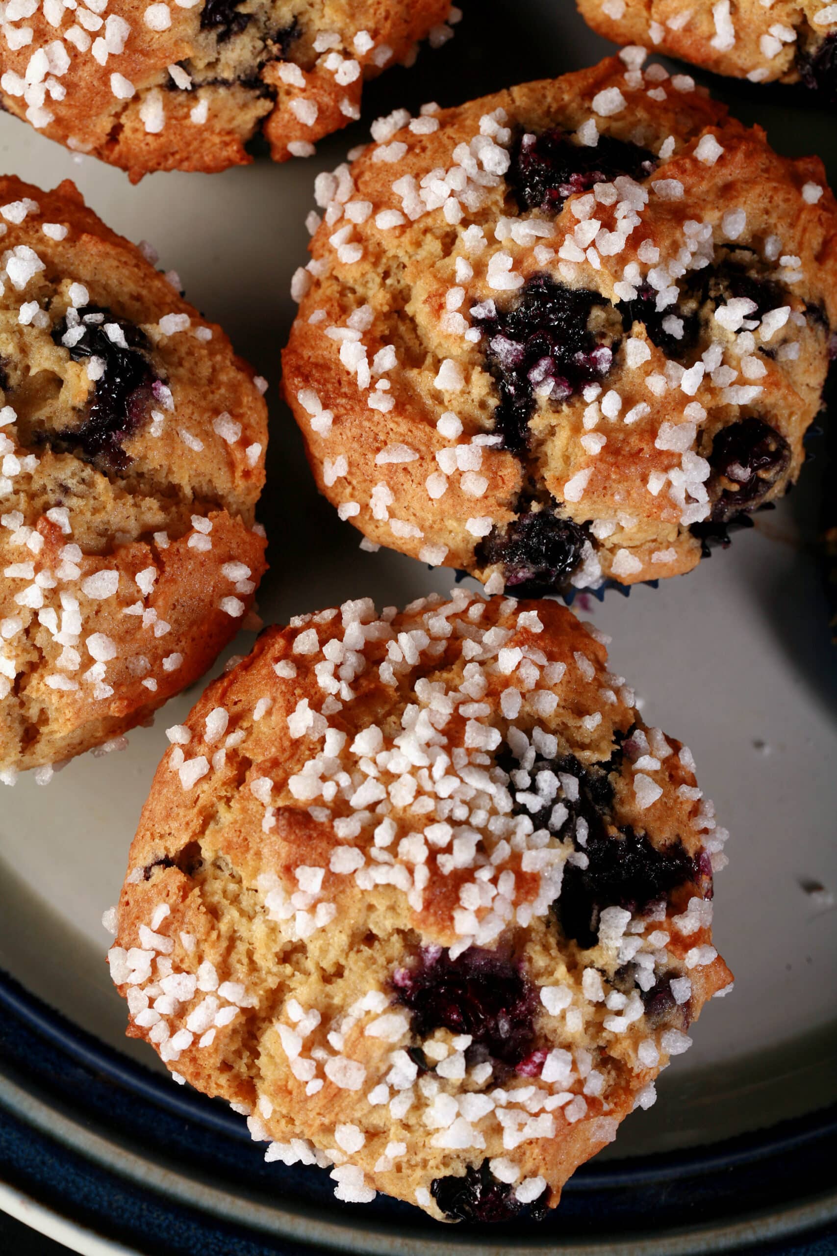 Several sugar topped gluten free blueberry muffins on a plate.