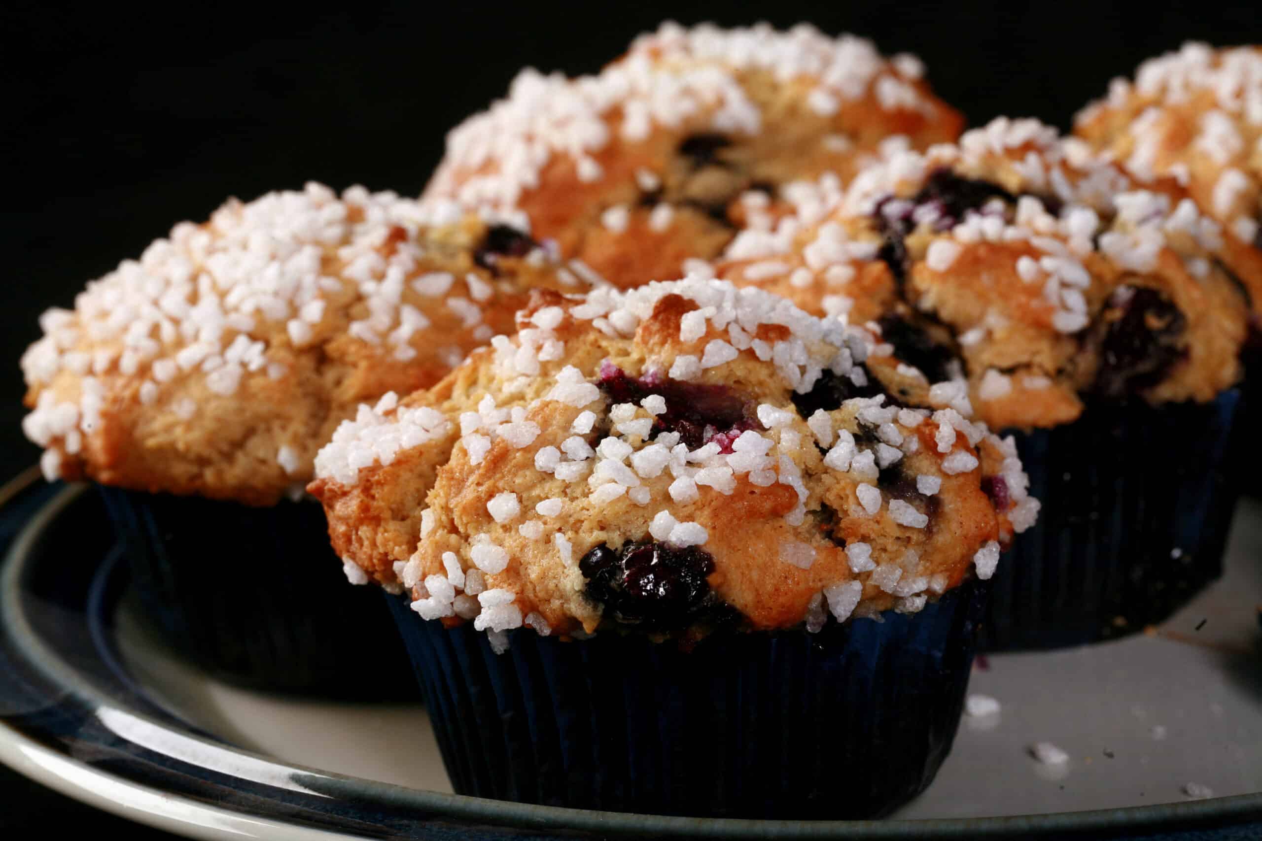 Several sugar topped gluten free blueberry muffins on a plate.