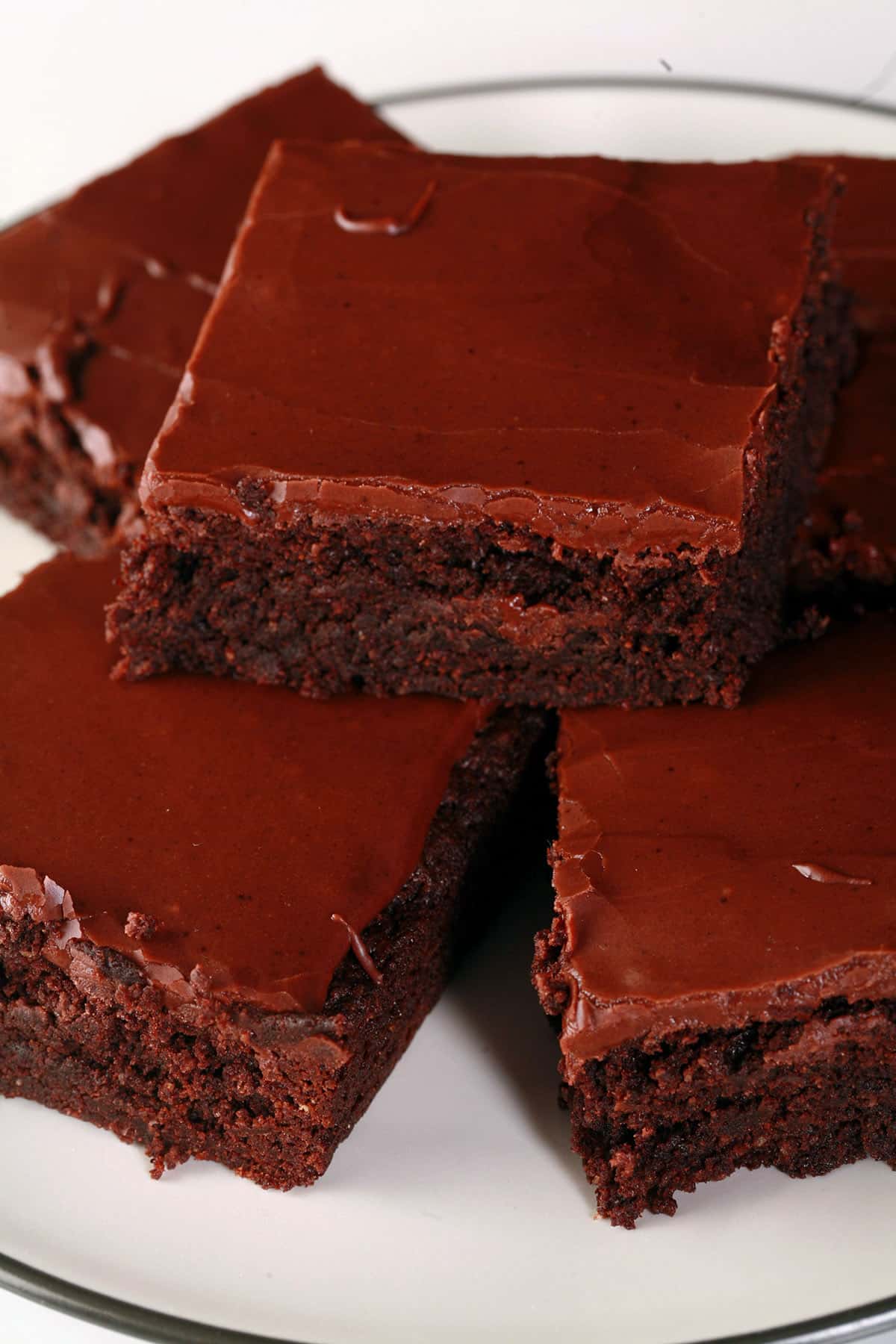 A plate of gluten-free brownies with chocolate frosting.