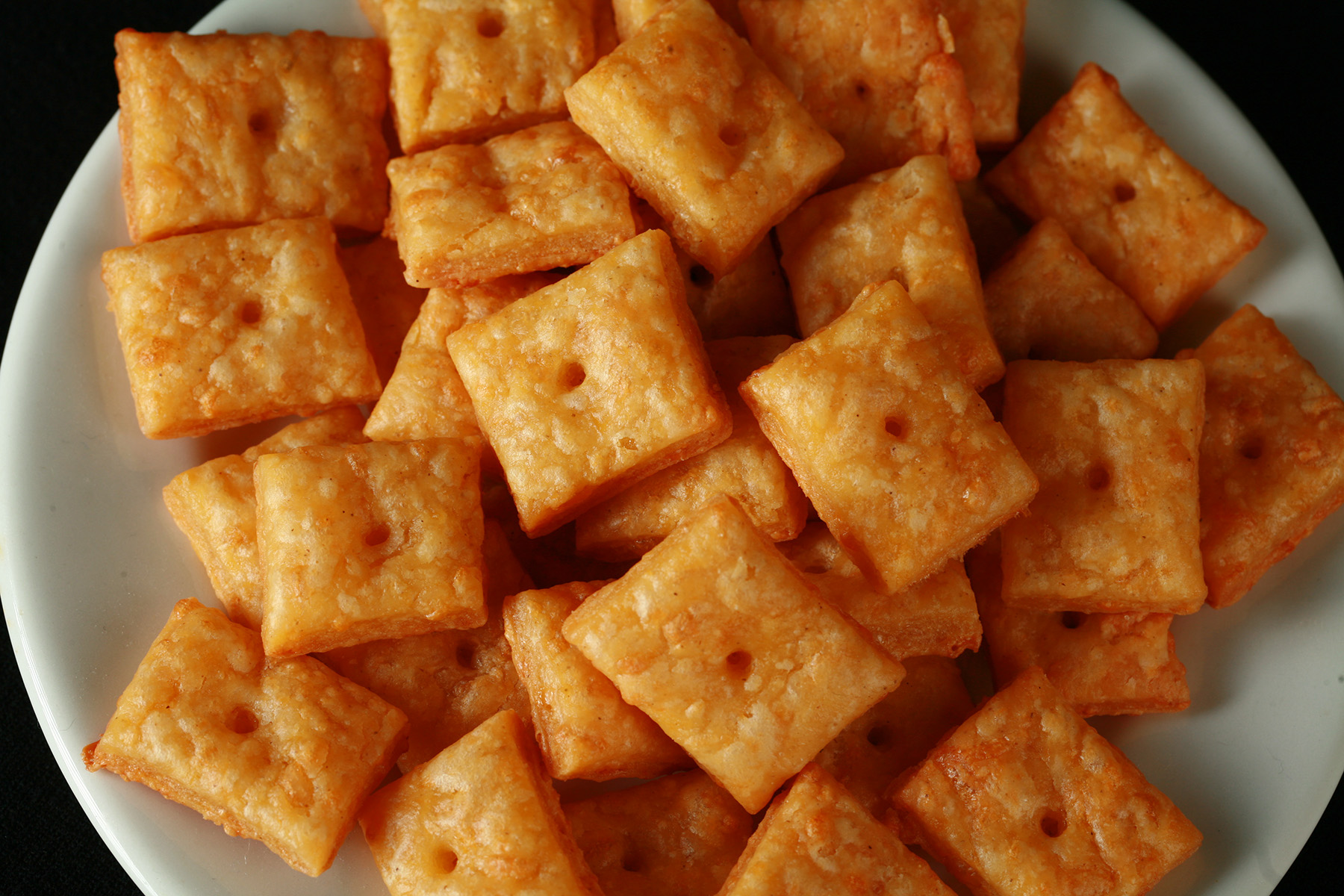 A pile of gluten-Free Cheez-its - little square gluten-free cheese crackers.