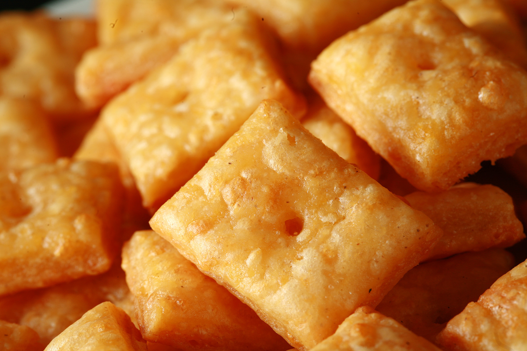 A pile of gluten-Free Cheez-its - little square gluten-free cheese crackers.