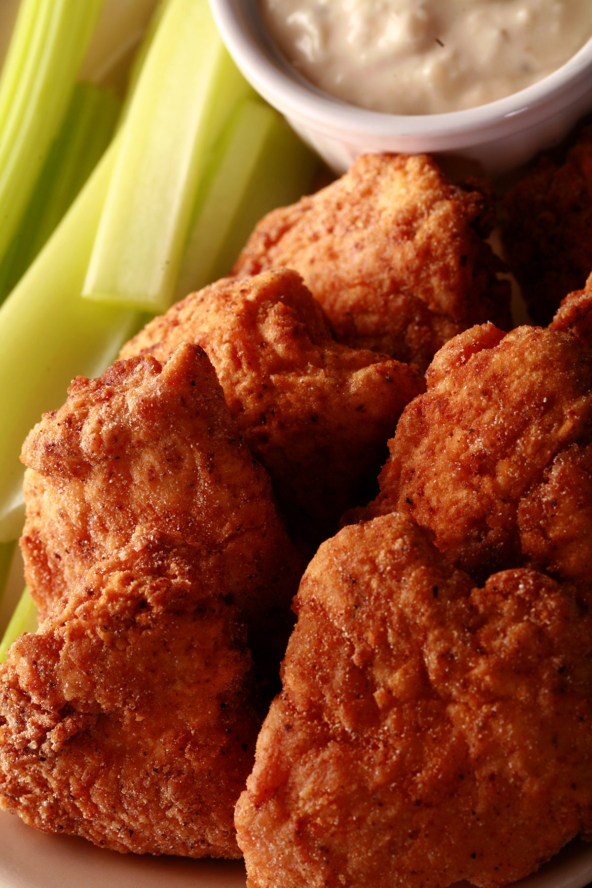 A plate of deep fried gluten-free chicken nuggets, celery, and dip.