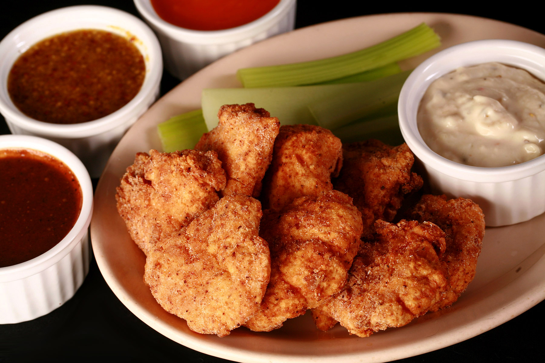 A plate of deep fried gluten-free chicken nuggets, celery, and dip.