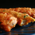 Several strips of gluten-free chicken pakora on a blue plate. They are golden deep fried, with flecks of green cilantro.