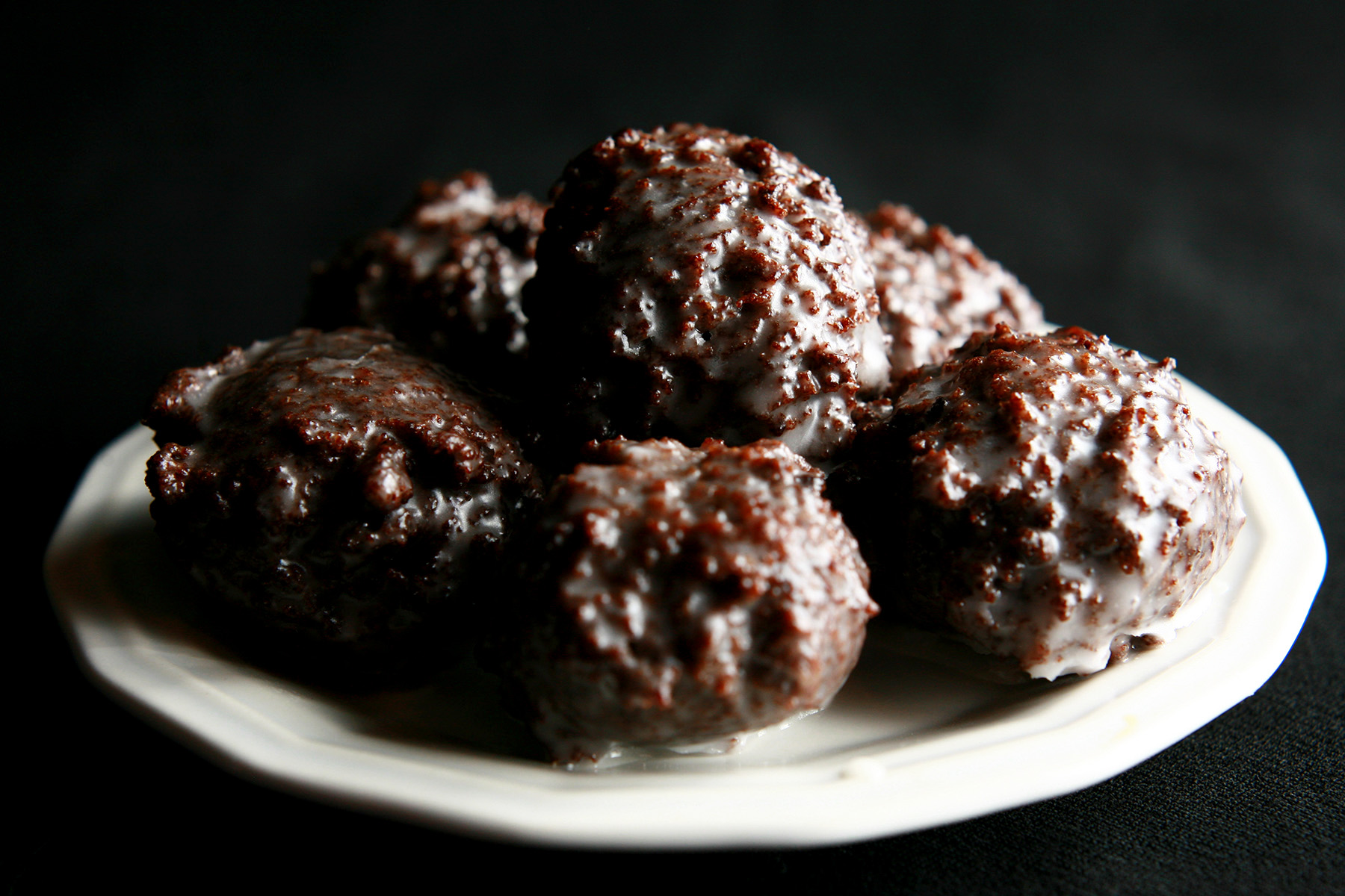 Several gluten-free chocolate doughnut holes on a small white plate.
