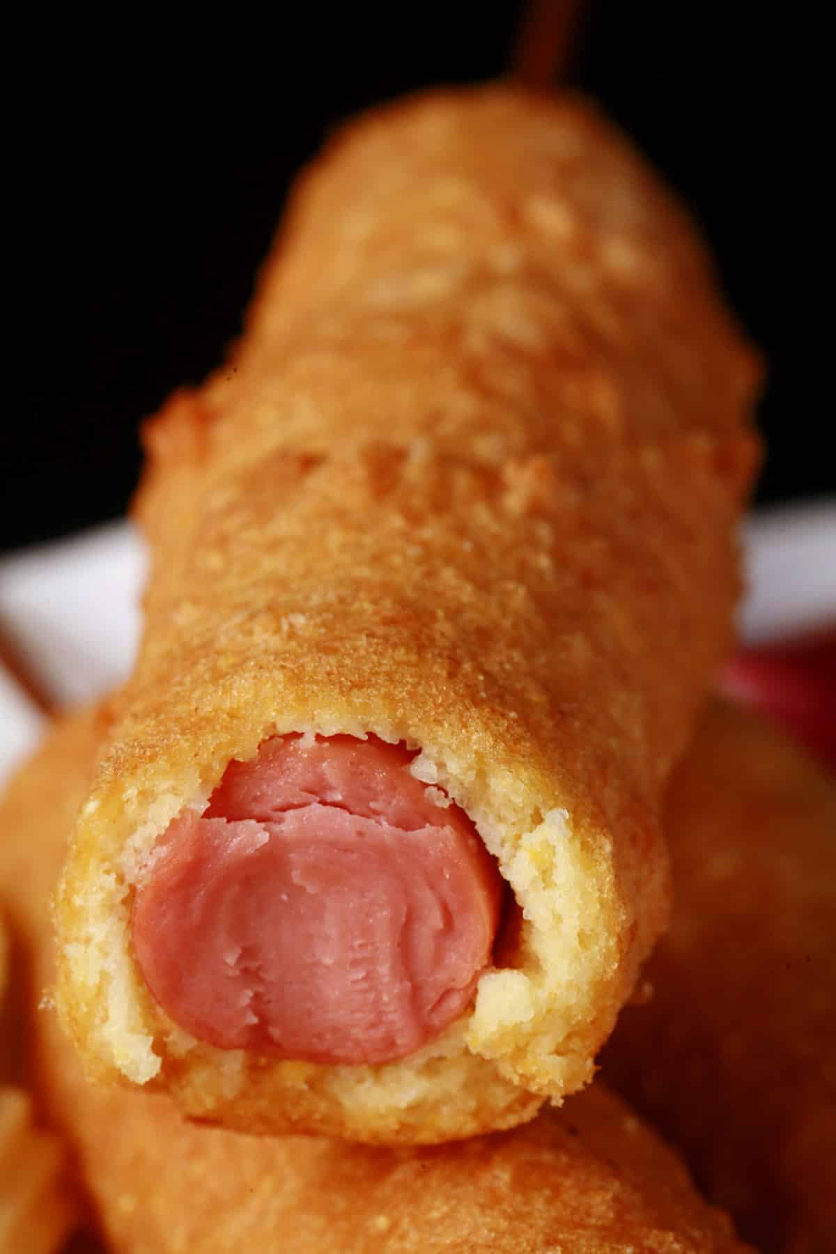 A close up photo of a gluten free corn dog that’s been bitten.