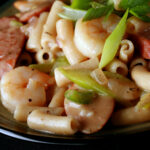 A plate of gluten-Free Creamy Creole Pasta. Shrimp, chicken, sausage, and celery are visible.