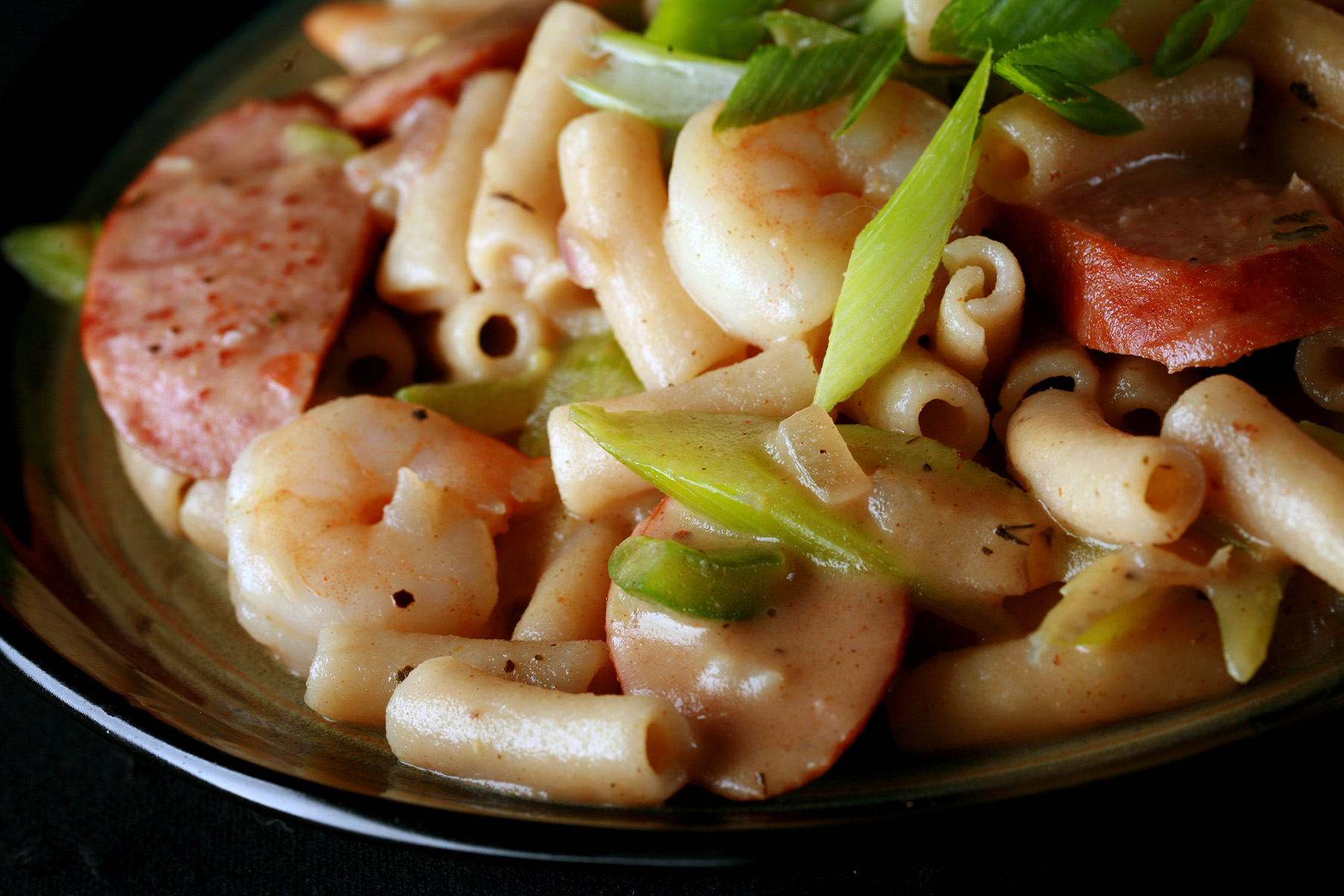 A plate of gluten-Free Creamy Creole Pasta. Shrimp, chicken, sausage, and celery are visible.