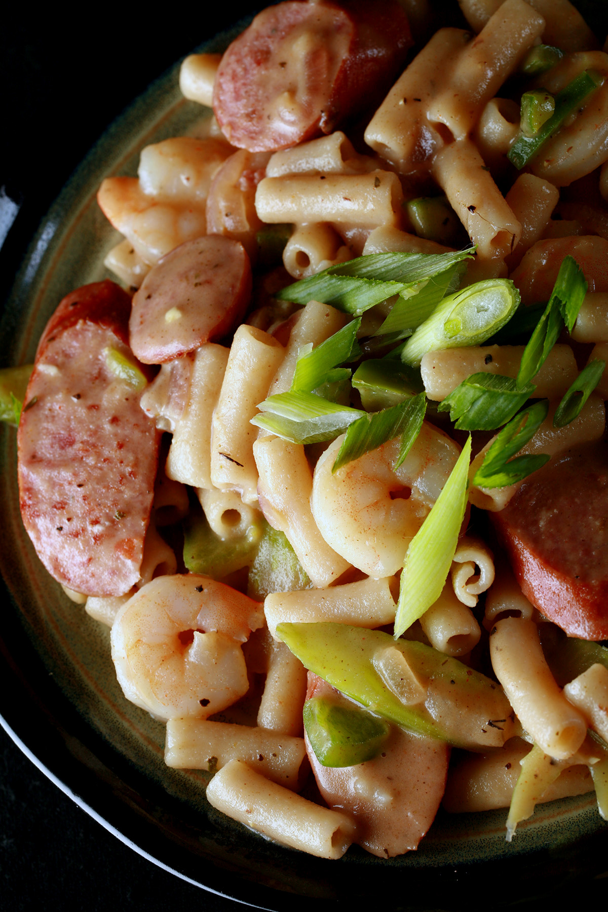 A plate of gluten-Free Creamy Creole Pasta. Shrimp, chicken, sausage, and celery are visible.