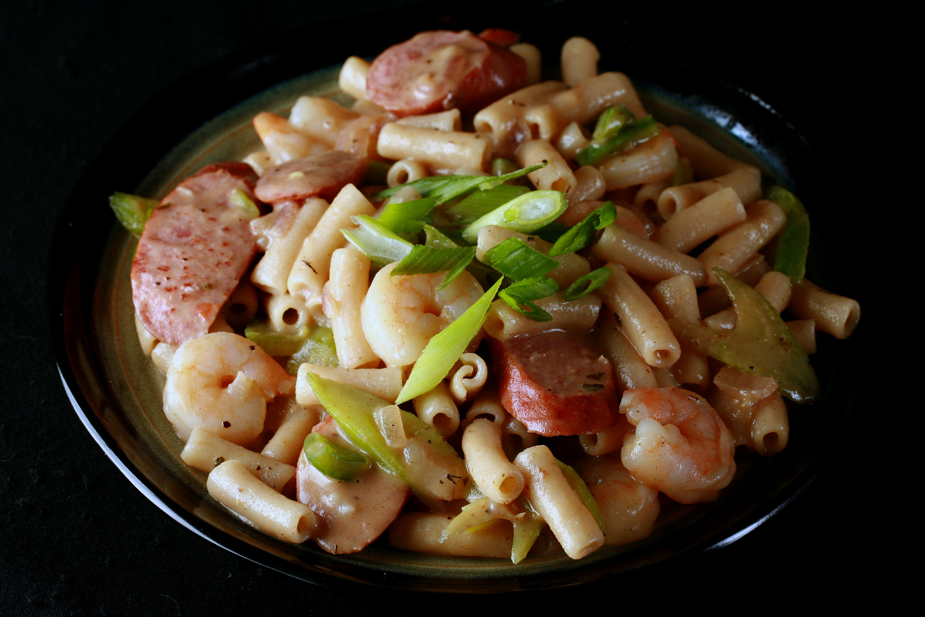 A plate of gluten-Free Creamy Creole Pasta. Shrimp, chicken, sausage, and celery are visible.