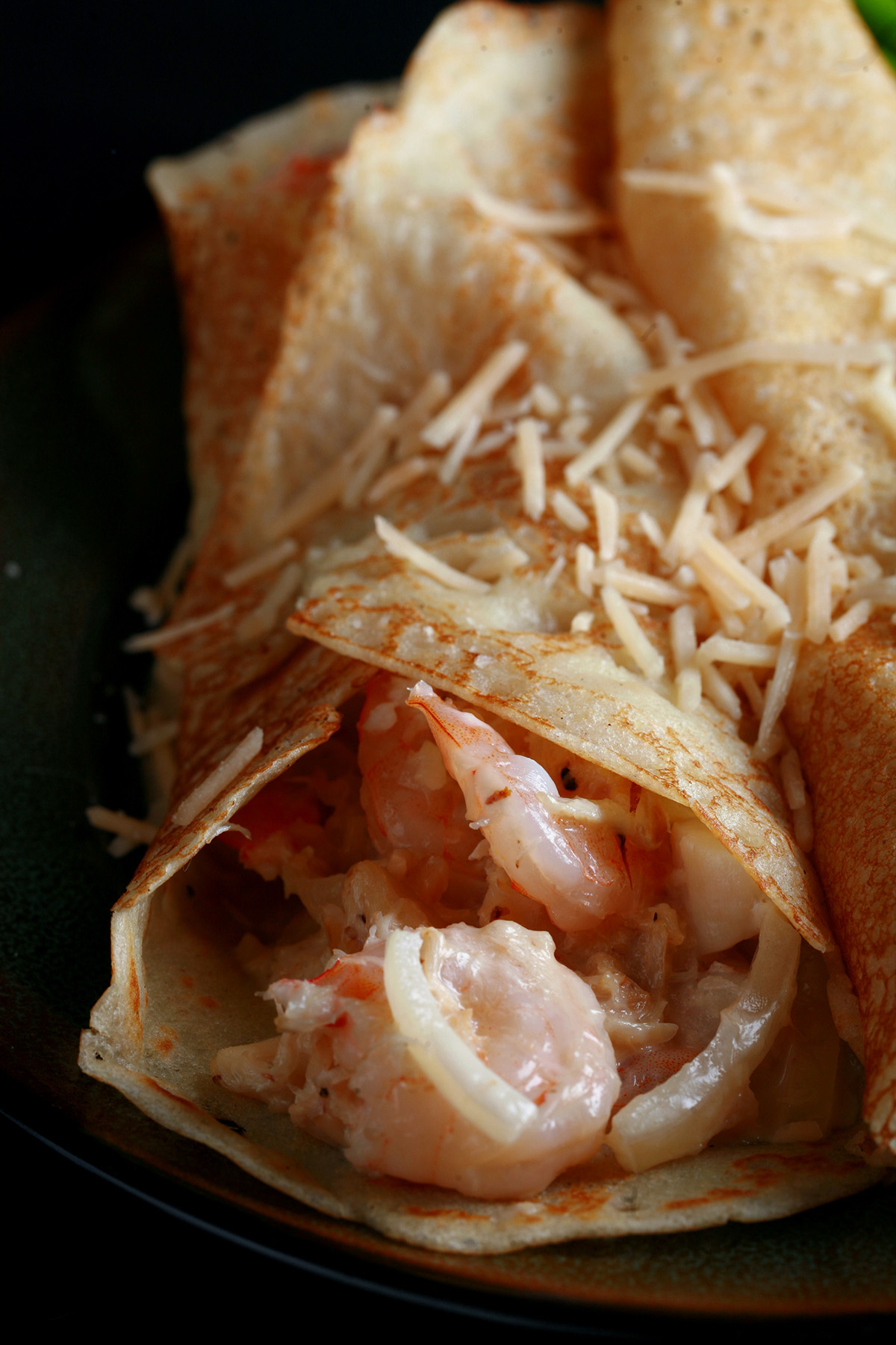 2 Gluten free seafood crepes with asparagus spears on the side.