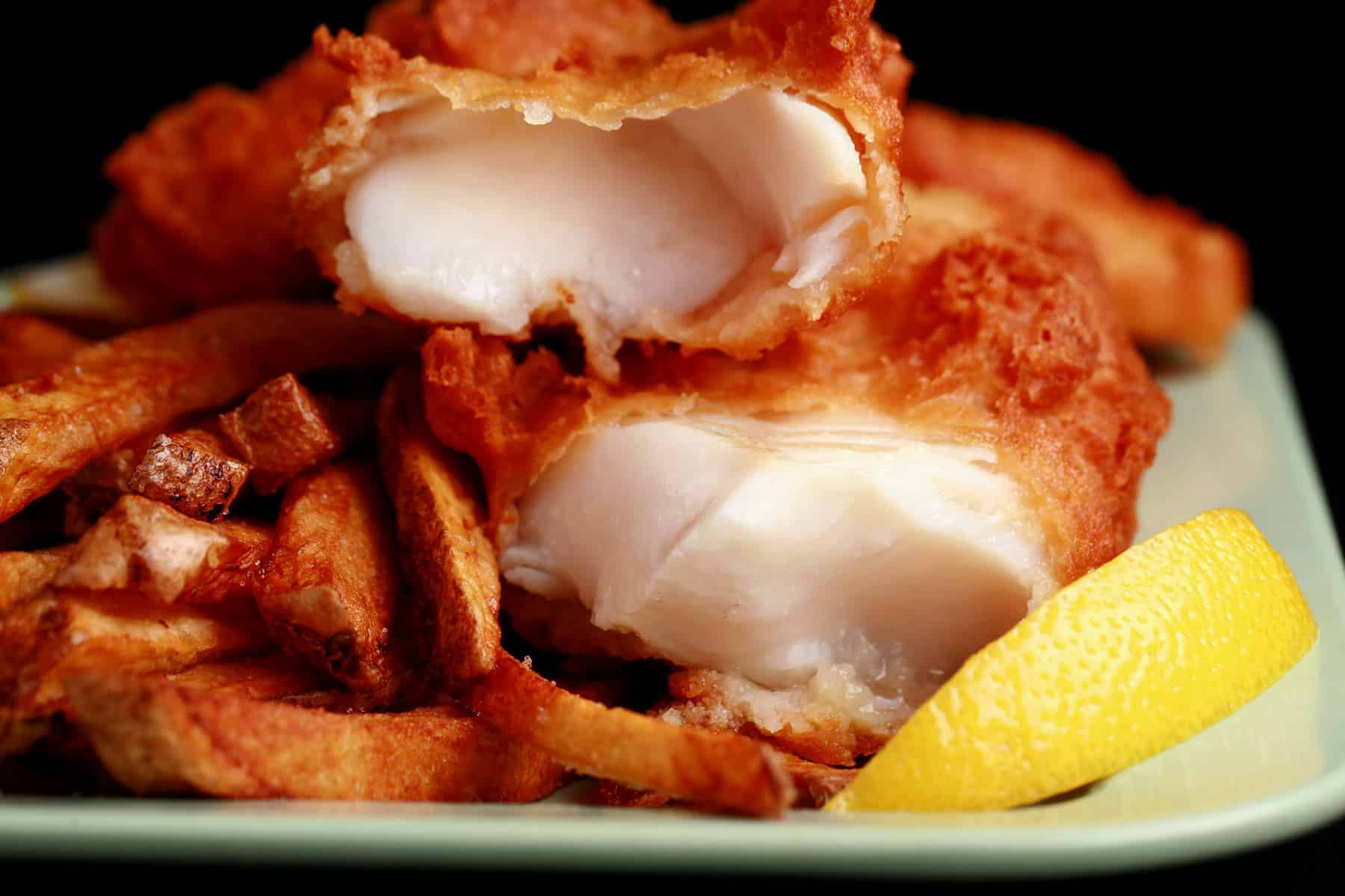 A plate of gluten-free fish and chips, with a wedge of lemon.