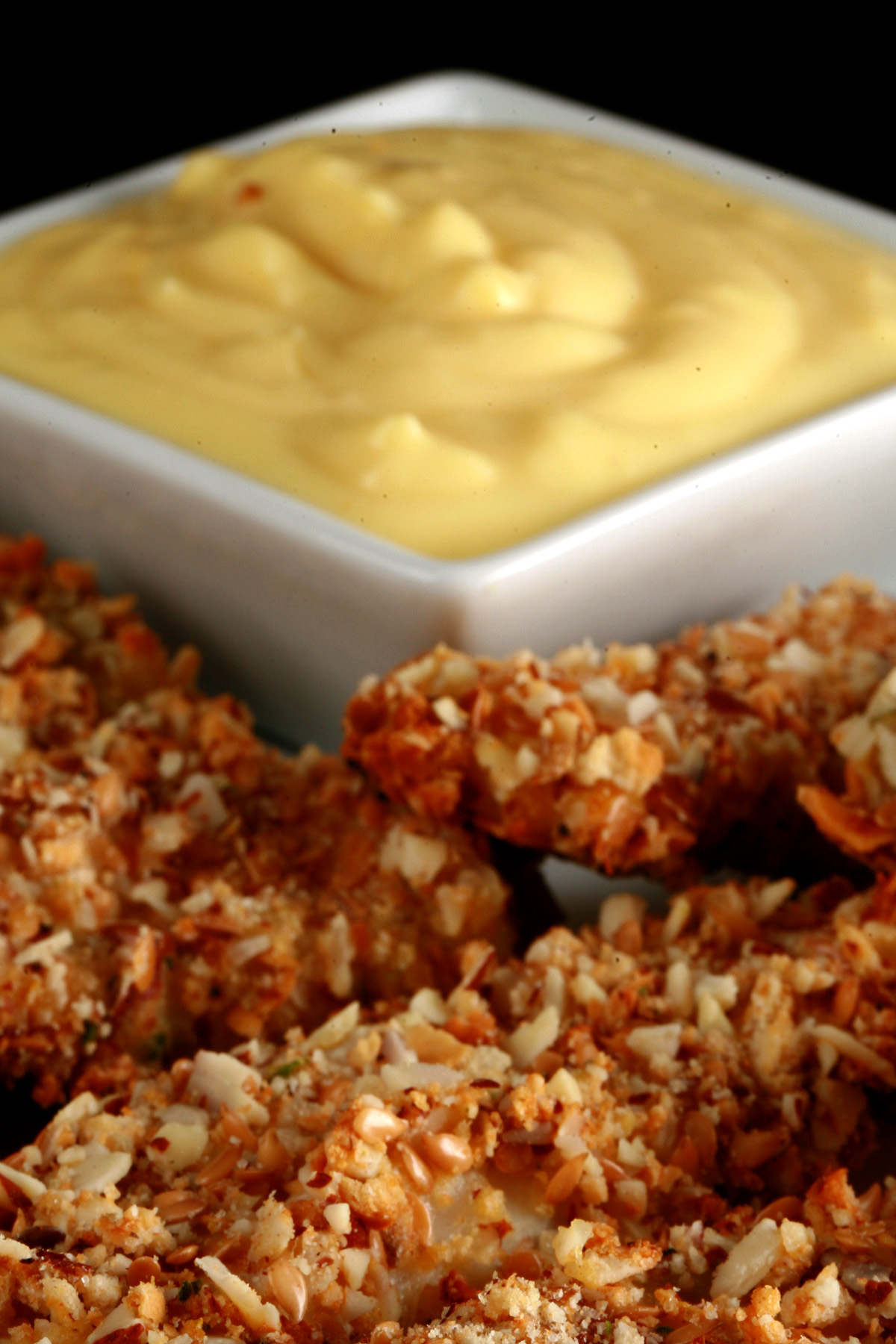 A plate of gluten-free fish fingers with a small bowl of savoury custard on the plate.