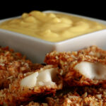 A plate of gluten-free fish fingers with a small bowl of savoury custard on the plate.