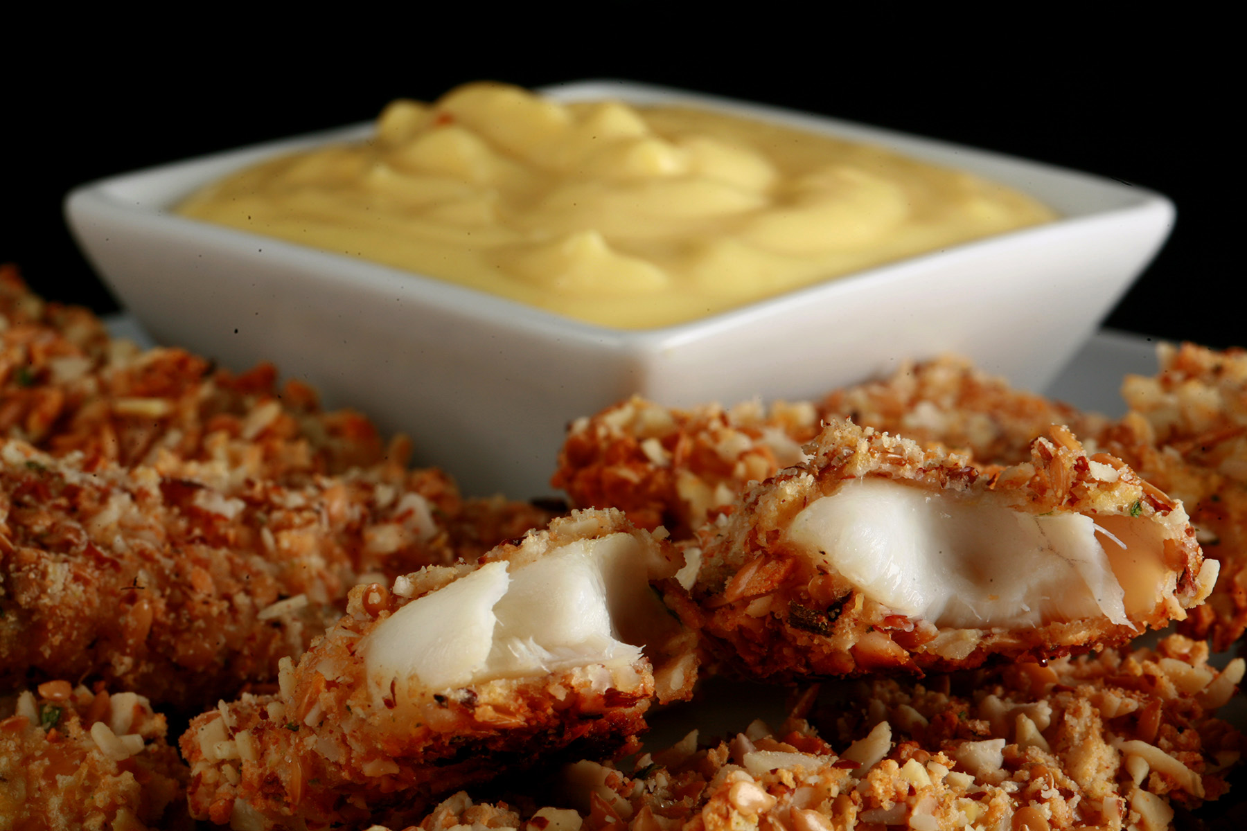 A plate of gluten-free fish fingers with a small bowl of savoury custard on the plate.