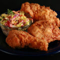 3 pieces of gluten-free fried chicken on a plate, next to a small bowl of colourful coleslaw.