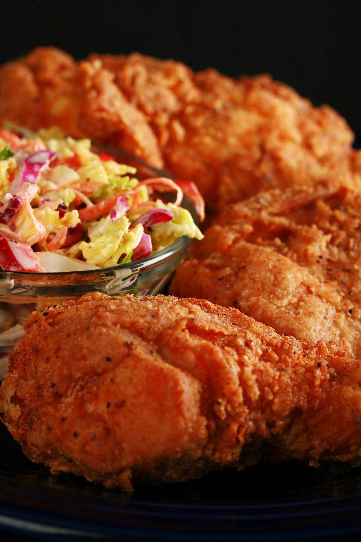 3 pieces of gluten-free fried chicken on a plate, next to a small bowl of colourful coleslaw.