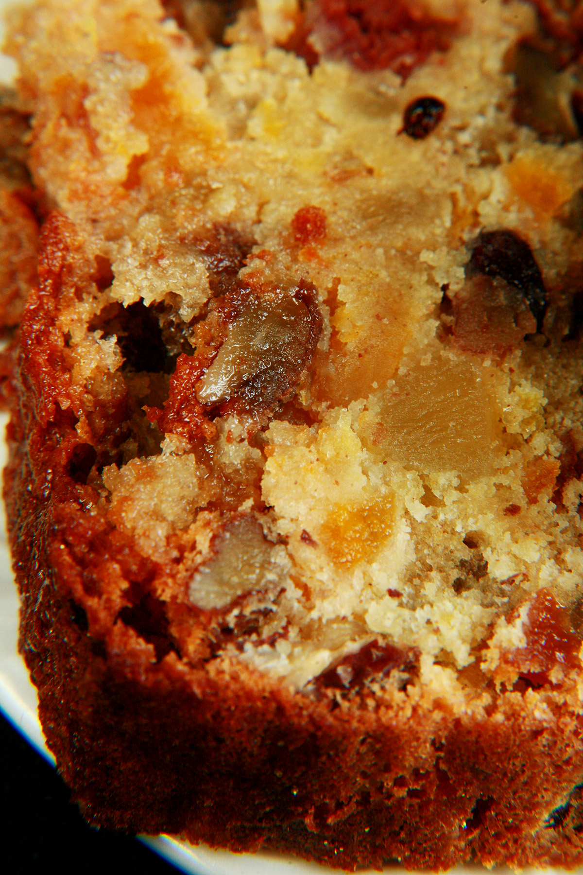 Slices of gluten free fruitcake, on a small white plate. The cake is generously studded with dried - not candied - fruit.
