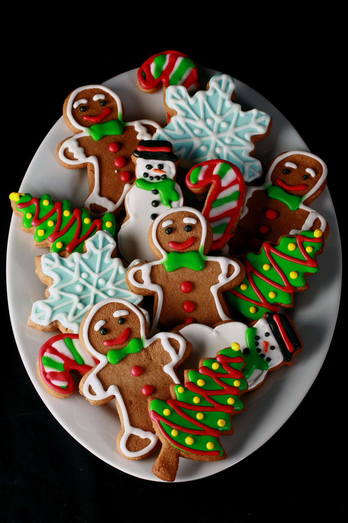 A plate of gluten-free gingerbread cookies, in various shapes, decorated with colourful royal icing.