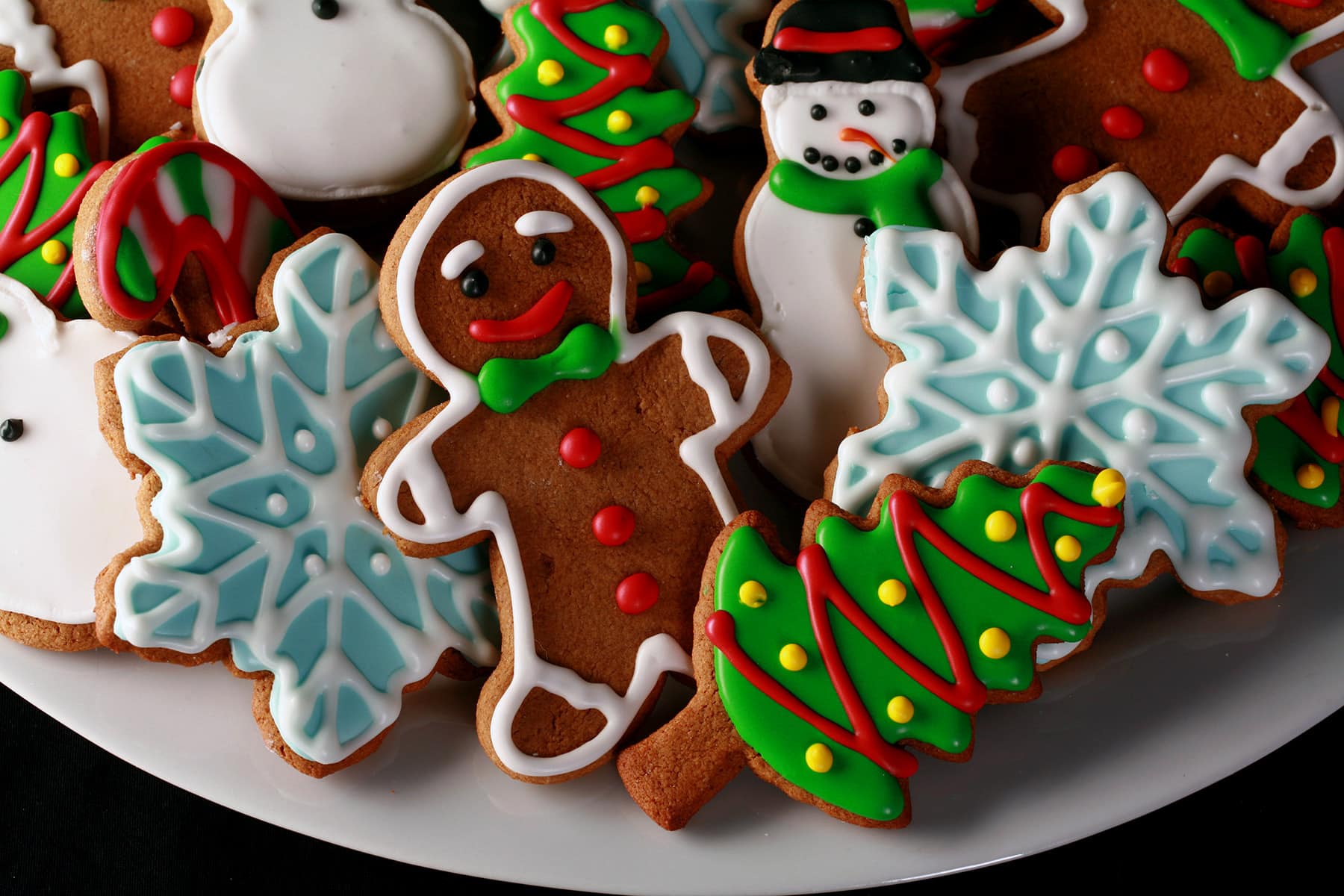 A plate of gluten-free gingerbread cookies, in various shapes, decorated with colourful royal icing.