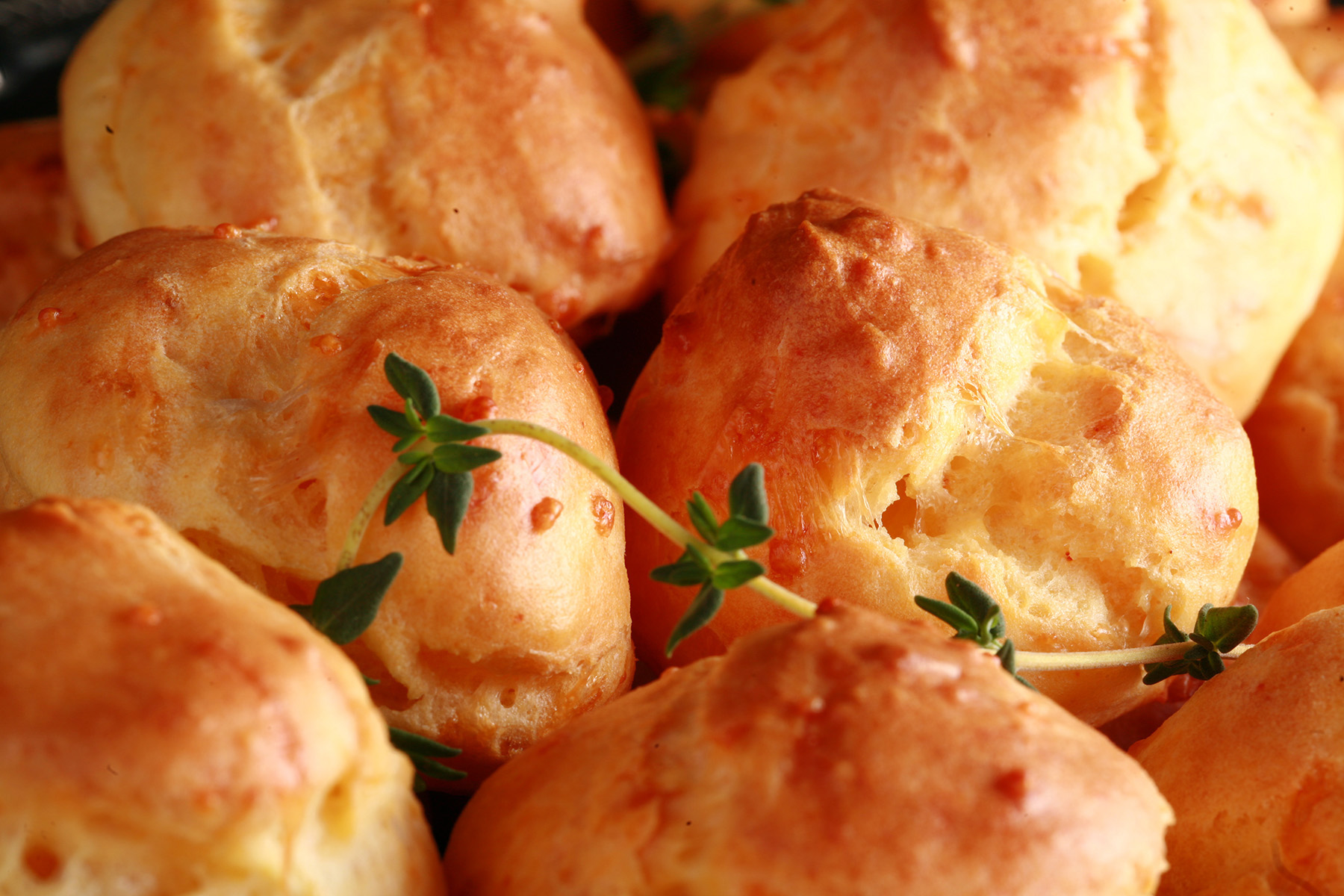 A large pile of Gluten-free Cheese Puffs - small, cheesy pastries - on a silver plate.