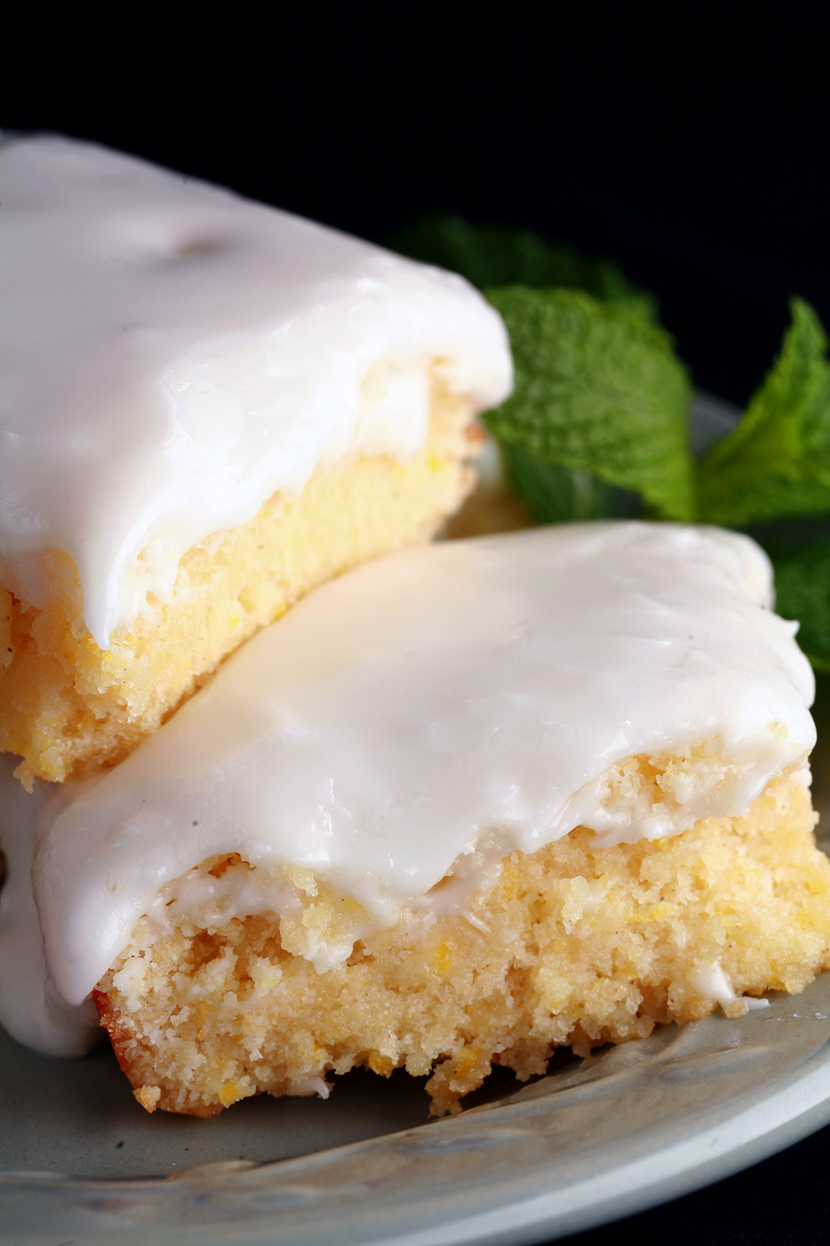 A plate of frosted gluten-free lemon bars, garnished with mint leaves.