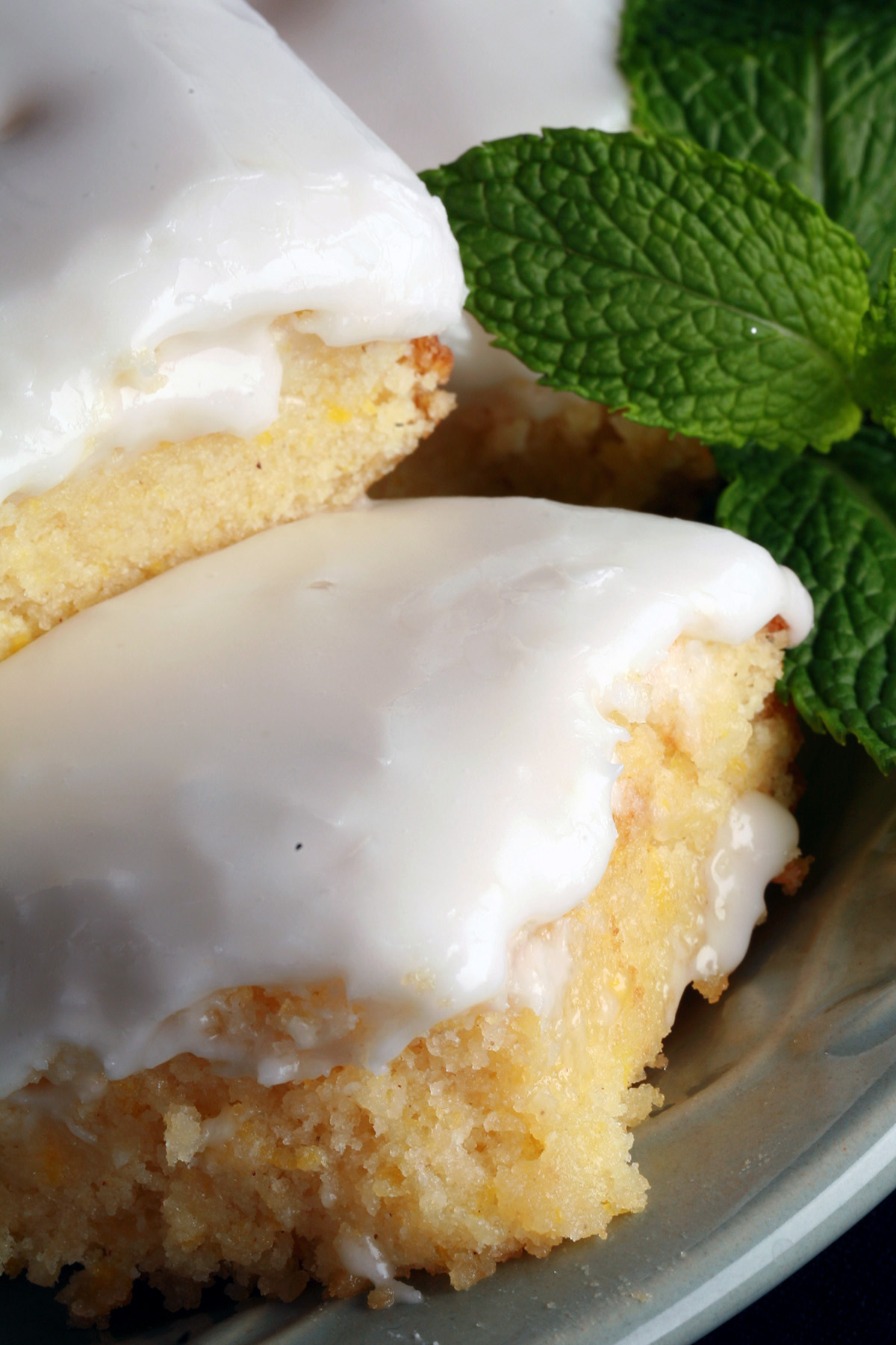 A plate of frosted gluten-free lemon bars, garnished with mint leaves.