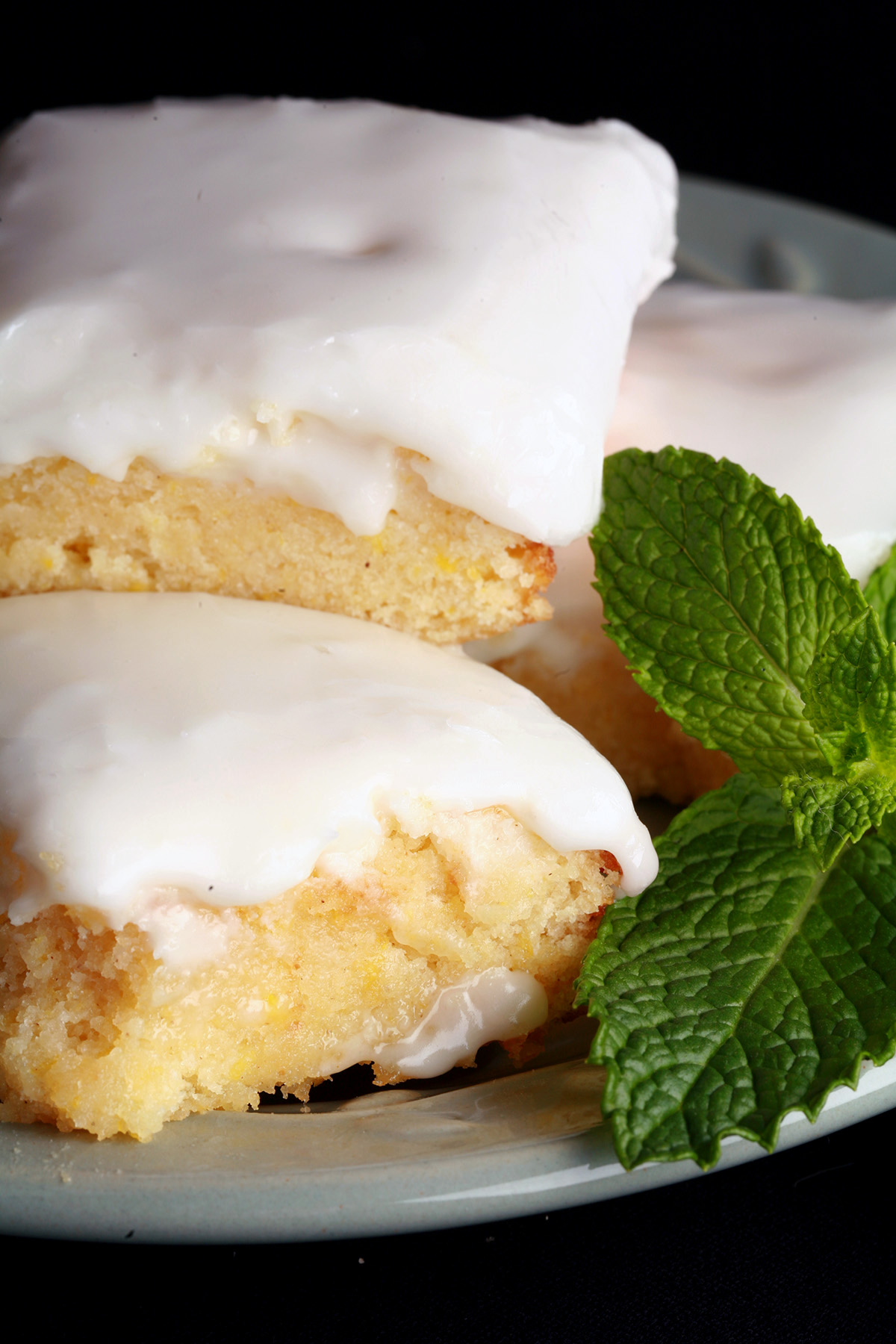 A plate of frosted chewy gluten-free lemon bars, garnished with mint leaves.