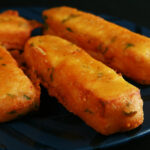 Several sticks of gluten-free paneer pakora - deep fried cheese sticks - on a blue plate.