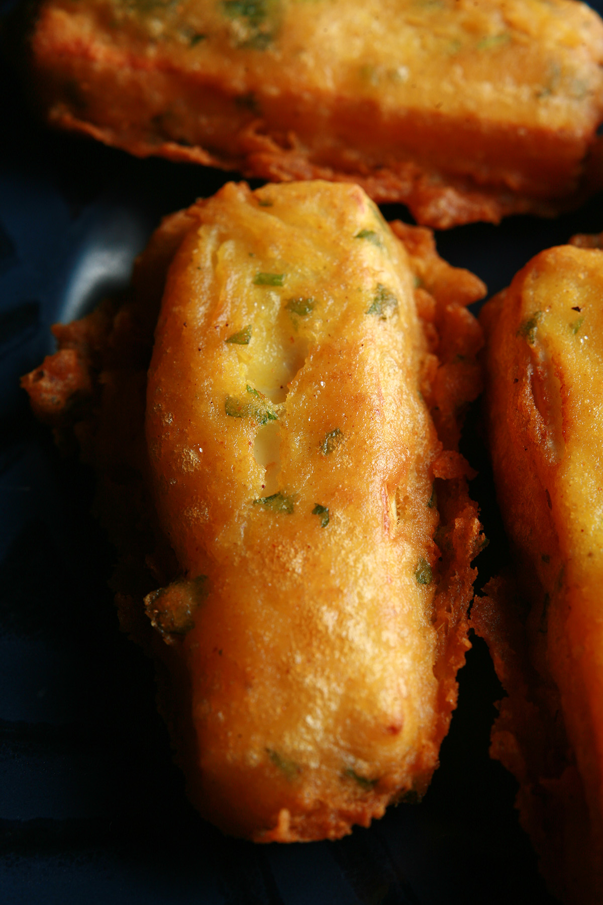 Several sticks of gluten-free paneer pakora - deep fried cheese sticks - on a blue plate.