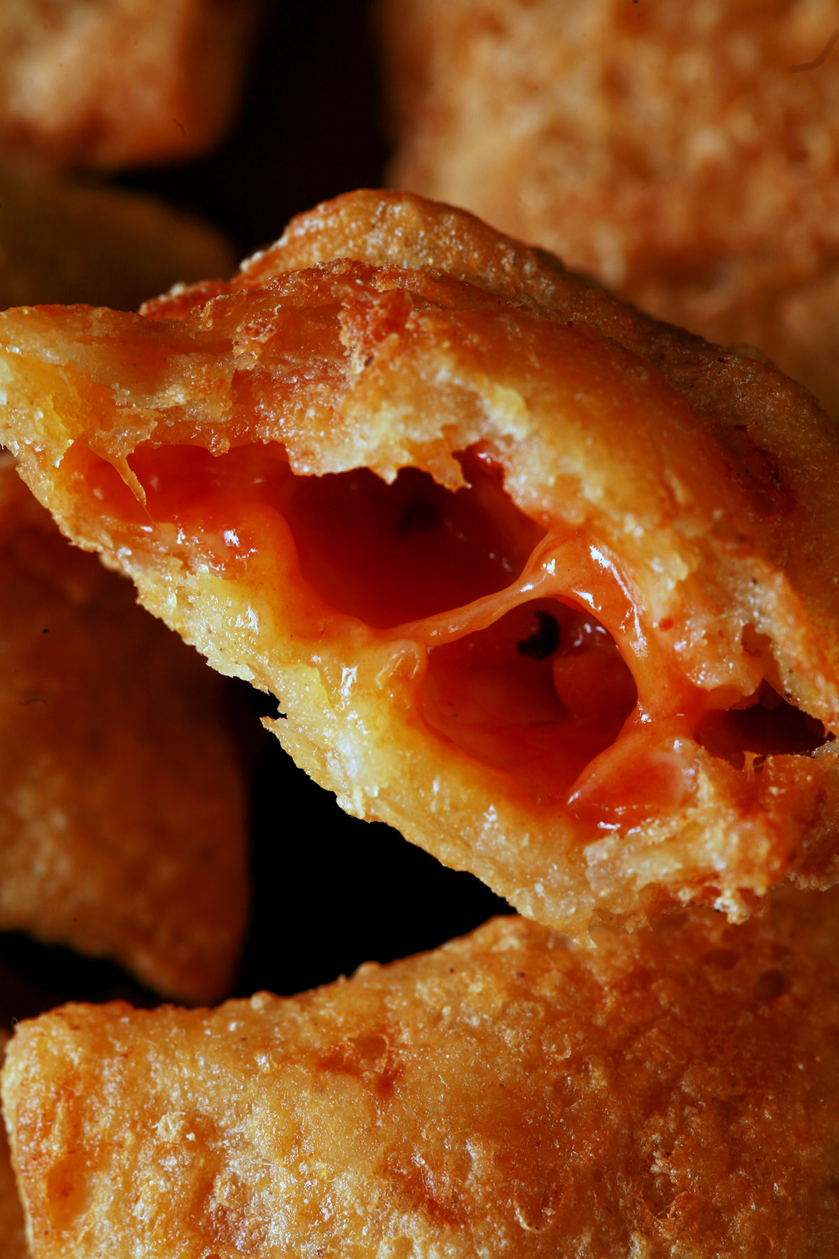 A plate with a pile of gluten-free pizza bites. One has been cut in half to show its pizza filling.